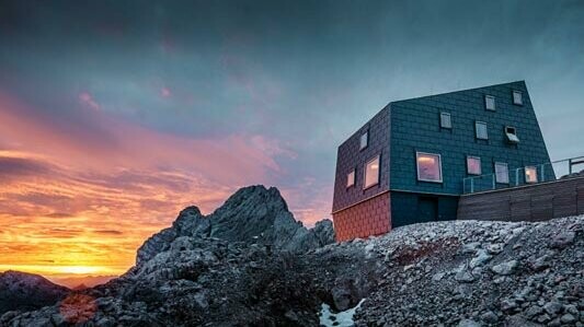 Izuzetna arhitektura u planinama: planinska kuća Seethalerhütte na planini Dachstein s PREFA krovnim i fasadnim panelima FX.12 u kameno sivoj boji.