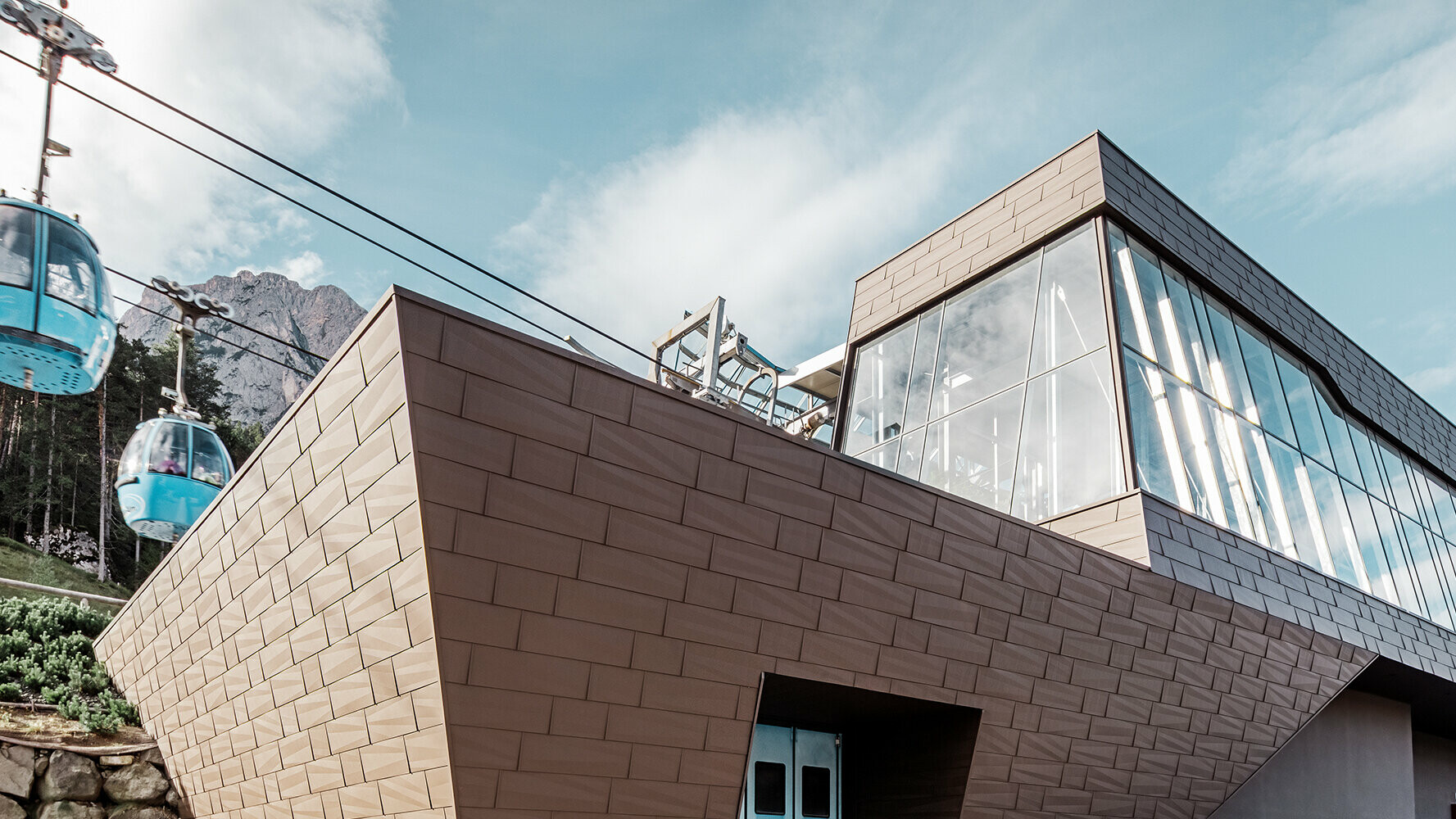 Donja stanica žičare u južnom Tirolu s modernom krovnom i fasadnom oblogom tvrtke PREFA u smeđoj boji.