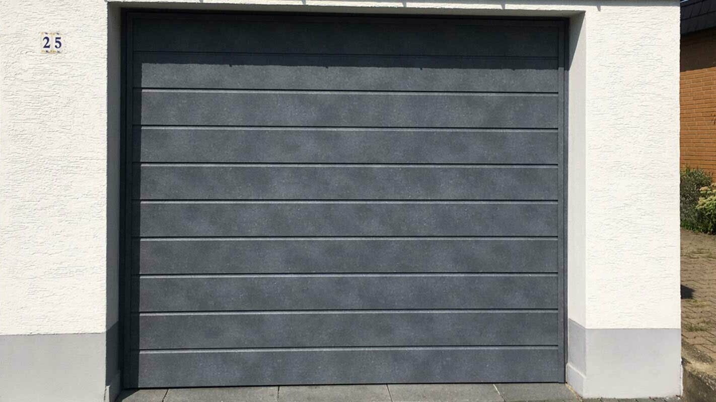 Garažna vrata obložena horizontalno položenim fasadnim kazetama Siding u kameno sivoj boji tvrtke PREFA