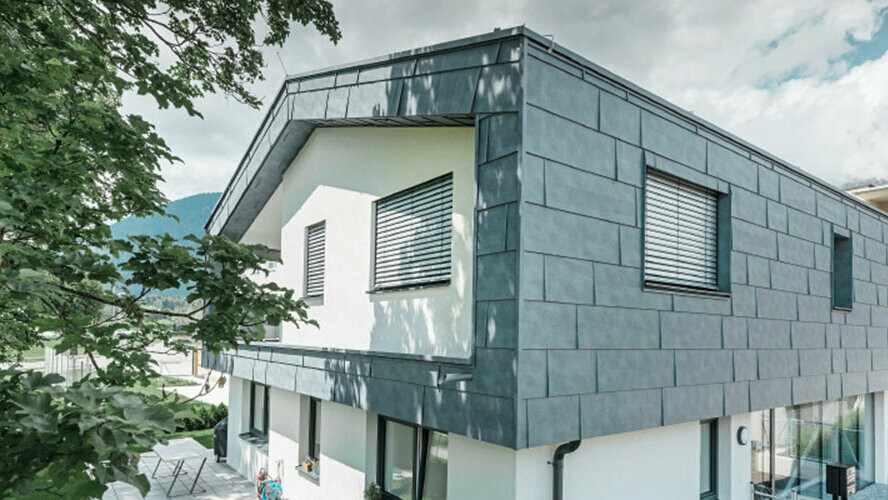 Prvi kat moderne stambene zgrade obložen PREFA aluminijskim fasadnim panelima FX.12 u kameno sivoj boji.