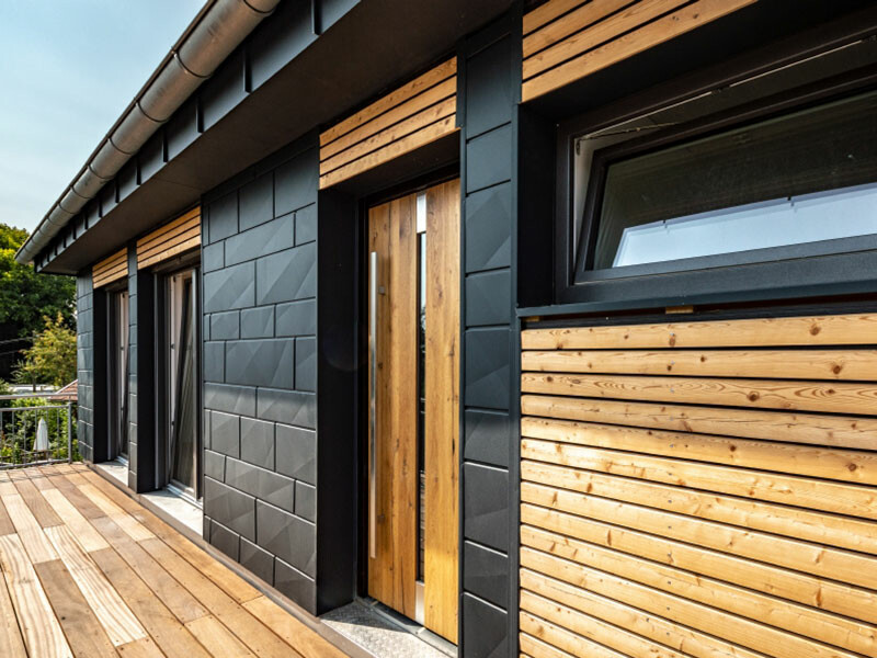 Moderna obiteljska kuća s lijepim PREFA fasadnim panelima Siding.X u antracit boji i elementima od drva.