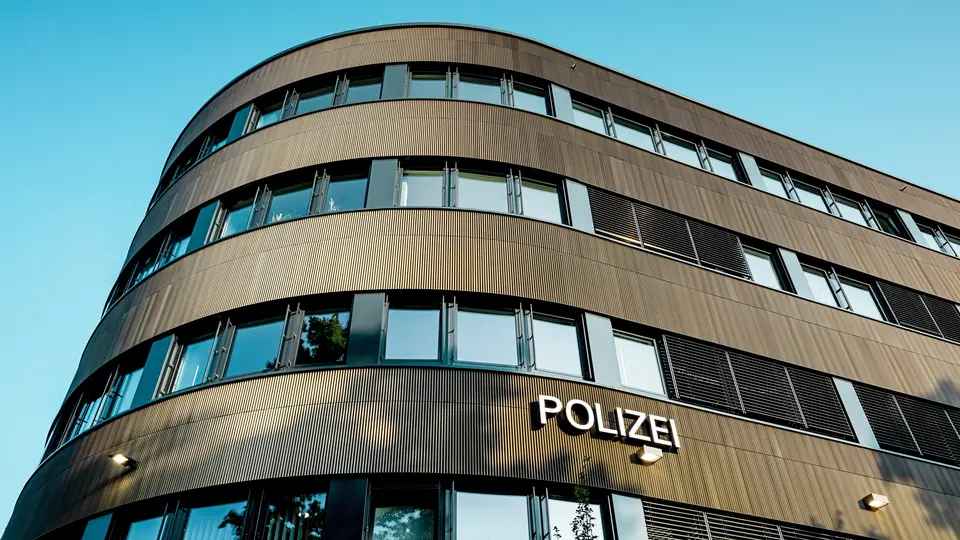 Dramatičan pogled ispod zakrivljenog novog dijela Policijske postaje 43 u Hamburgu otkriva upečatljivu PREFA aluminijsku fasadu od eloksiranih ekstrudiranih zupčastih profila u srednje brončanoj nijansi. Kao snažan arhitektonski element, fasada privlači pažnju svojom finom, ritmičnom strukturom koja stvara dinamičnu igru svjetla i sjene te naglašava fluidne zaobljene oblike građevine. PREFA aluminij pruža izvrsnu otpornost na vremenske uvjete i koroziju, iznimnu dugotrajnost te predstavlja održivo rješenje s minimalnim zahtjevima za održavanje za precizno oblikovane, suvremene fasade.