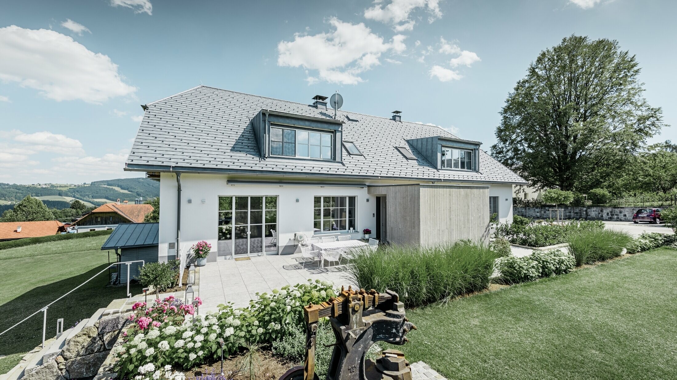 Klasična obiteljska kuća s dvostrešnim krovom s lastavicama; Kuća sa saniranim krovom s PREFA krovnom šindrom u kameno sivoj boji s lijepo uređenom okućnicom i prostranom terasom.