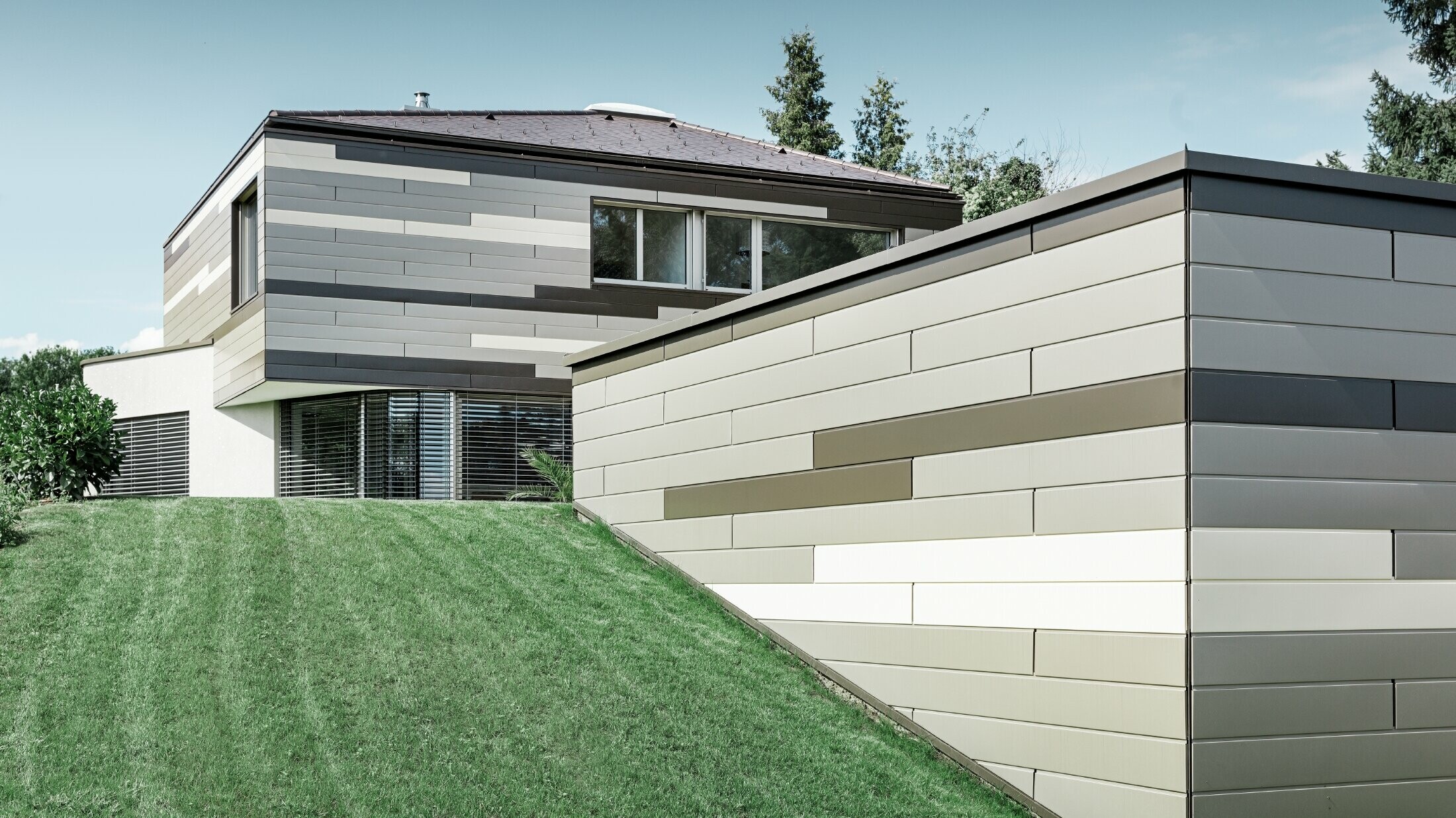 Moderna obiteljska kuća s ravnim krovom i natkrivenom terasom, s individualno oblikovanom aluminijskom fasadom iz fasadnih kazeta u smeđoj boji, boji bronce i slonovače od PREFE