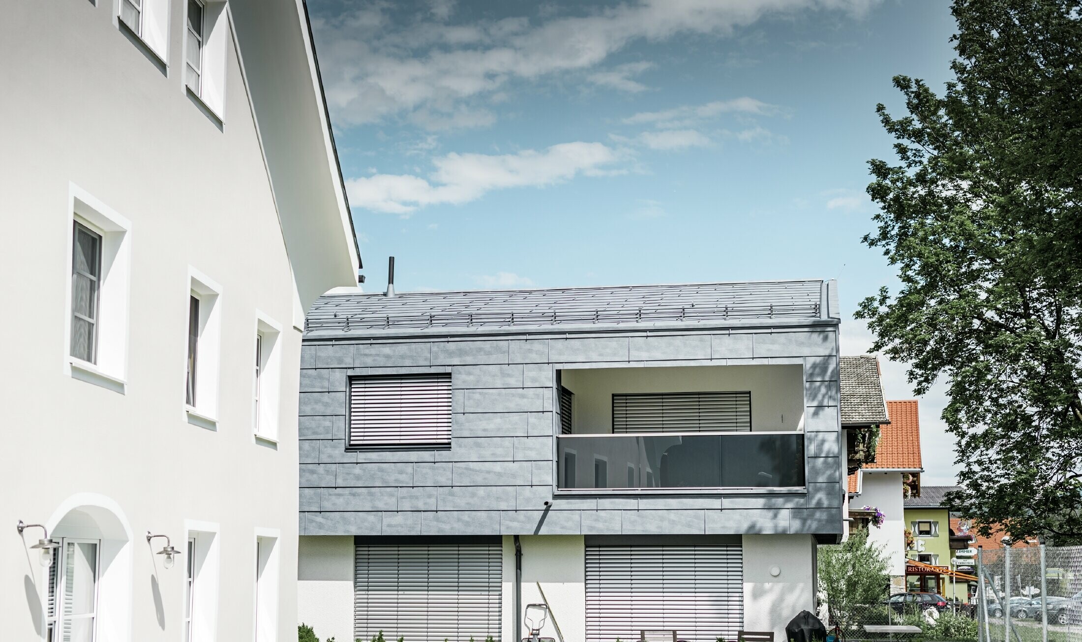 Na ovoj stambenoj kući u Miemingu cijeli gornji dio zgrade obložen je PREFA fasadnim panelom FX.12 u kameno sivoj.
