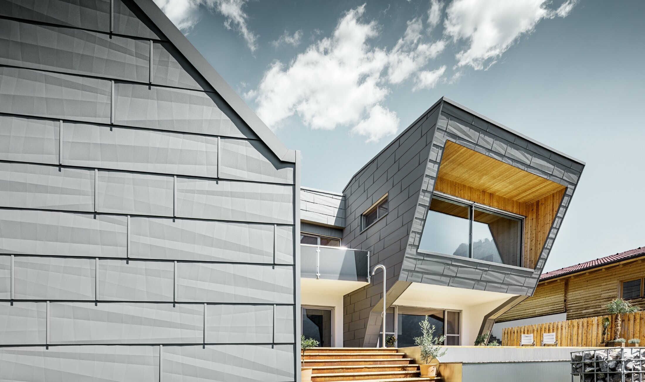 Svijetlo siva fasada na obiteljskoj kući u Lienzu - obloga s PREFA fasadnim panelom FX.12 u P.10 svijetlo sivoj u kombinaciji s drvenom fasadom.