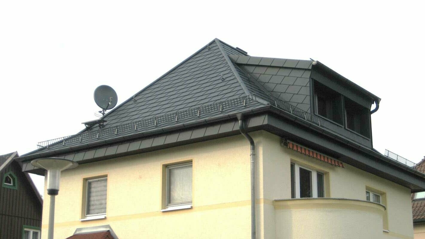 Sanacija četverostrešnog krova PREFA krovnom šindrom s krovnom kućicom, žuta fasada