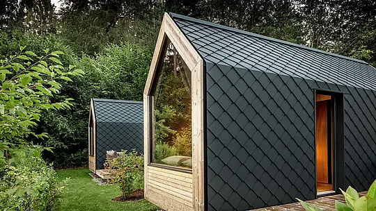 Dvije minimalističke tiny kuće Secret Koi Gardena smještene su u bujnom zelenilu na jezeru Natterer See. Fasade i krovovi u potpunosti su obloženi sitnim PREFA aluminijskim rombovima u P.10 antracitnoj boji, koji stvaraju upečatljivu strukturu nalik ribljoj koži.  Velike staklene površine i topli drveni detalji stvaraju zanimljiv kontrast tamnom aluminiju. Trajni i vremenski otporni PREFA aluminij pouzdano štiti objekt te naglašava visokokvalitetnu glamping arhitekturu.