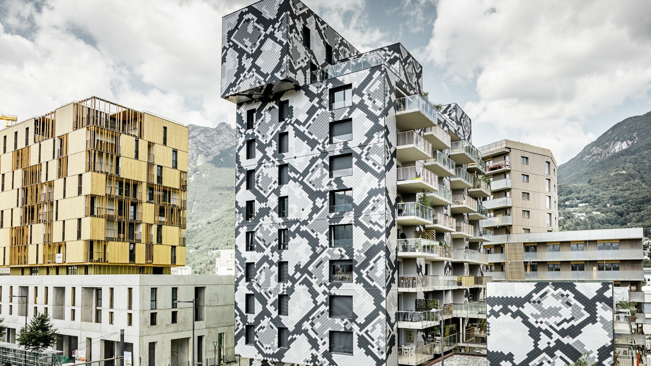 Impresivno oblikovanje fasade na stambenoj zgradi „le Python“ s uzorkom zmijske kože; Fasada je izrađena s PREFA zidnim rombovima u bojama antracit, svijetlo siva, prirodni aluminij i srebrna metalik.
