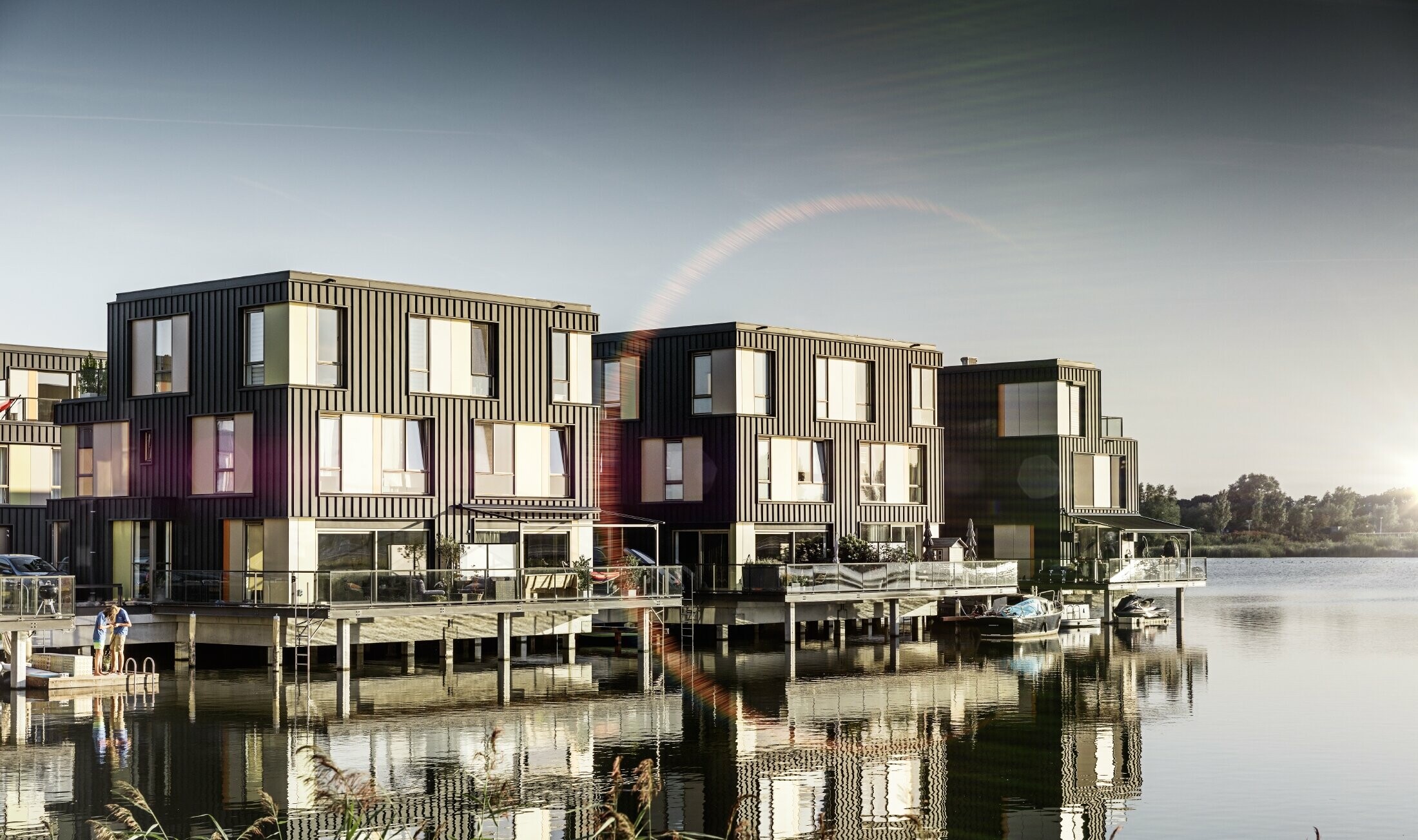 Naselje s dvostambenim zgradama na jezeru obloženim Prefalzom tvrtke PREFA u P.10 antracit boji.