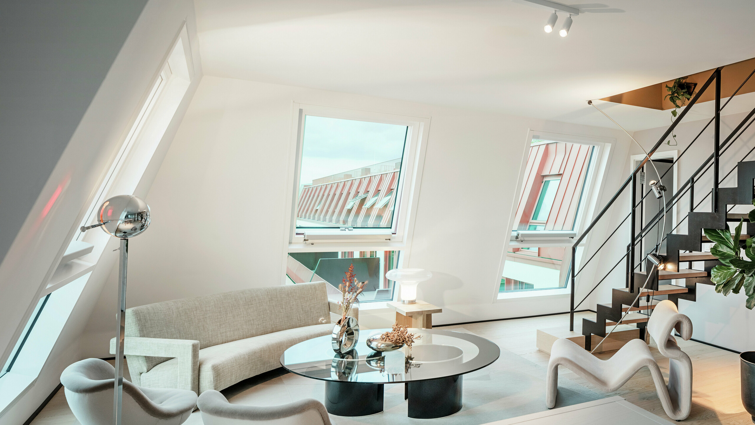 Unutarnji pogled na penthouse ispunjen prirodnim svjetlom u stambenom projektu Van B u Münchenu s pogledom na visokokvalitetni PREFALZ aluminijski krov u posebnoj boji IGP Orange HDP. Velike staklene površine propuštaju obilje dnevnog svjetla i naglašavaju moderan koncept stanovanja. Čiste linije, dizajnerski namještaj i precizna izvedba spojeva krova pokazuju kako se visokokvalitetna i stilska arhitektura može ostvariti ne samo izvana, već i iznutra.