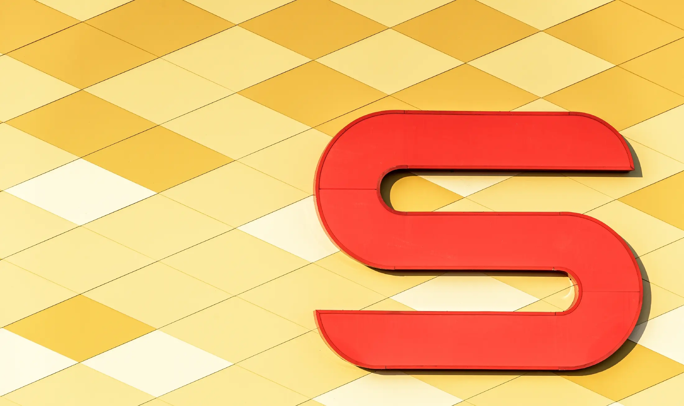 Spar podružnica s kariranom aluminijskom fasadom u žuto-narančastoj boji i Spar Logotipom