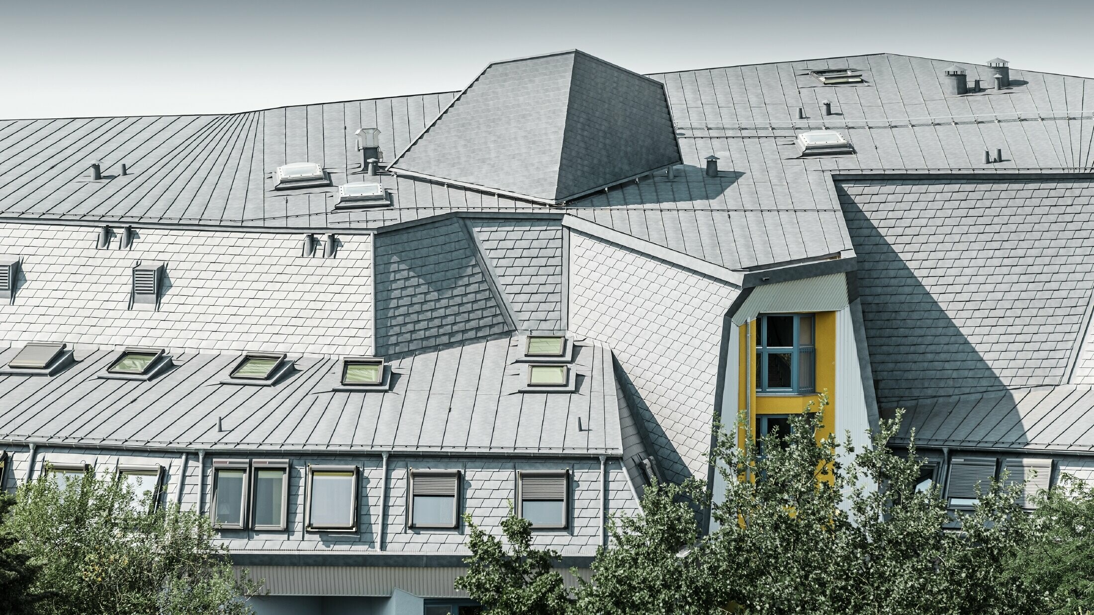 Složena krovna površina s krovnim kućicama i kutovima na kući Aja Textor-Goethe, pokrivena PREFA krovnom šindrom i Prefalzom u kameno sivoj