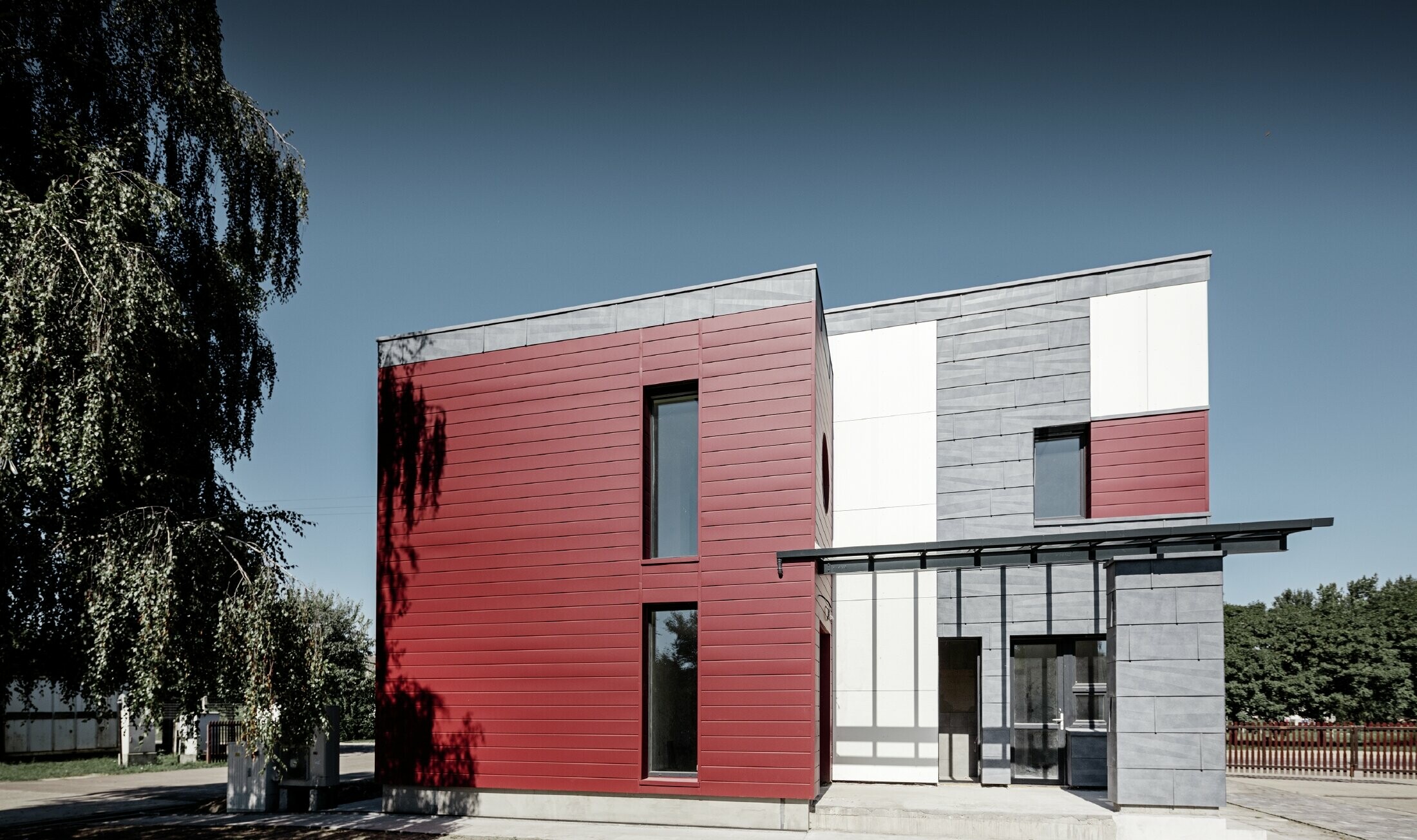 Moderna uredska zgrada s višedjelnom fasadom u crvenoj, kameno sivoj i bijeloj boji, s aluminijskim proizvodima fasadnim kazetama, fasadnim panelom FX.12 i aluminijskom kompozitnom pločom od PREFE