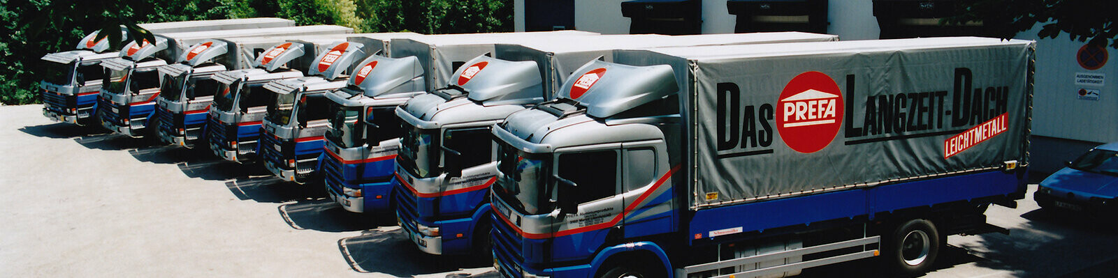 Osam nekadašnjih PREFA kamiona u plavoj i srebrnoj s PREFA logotipom stoje u nizu 