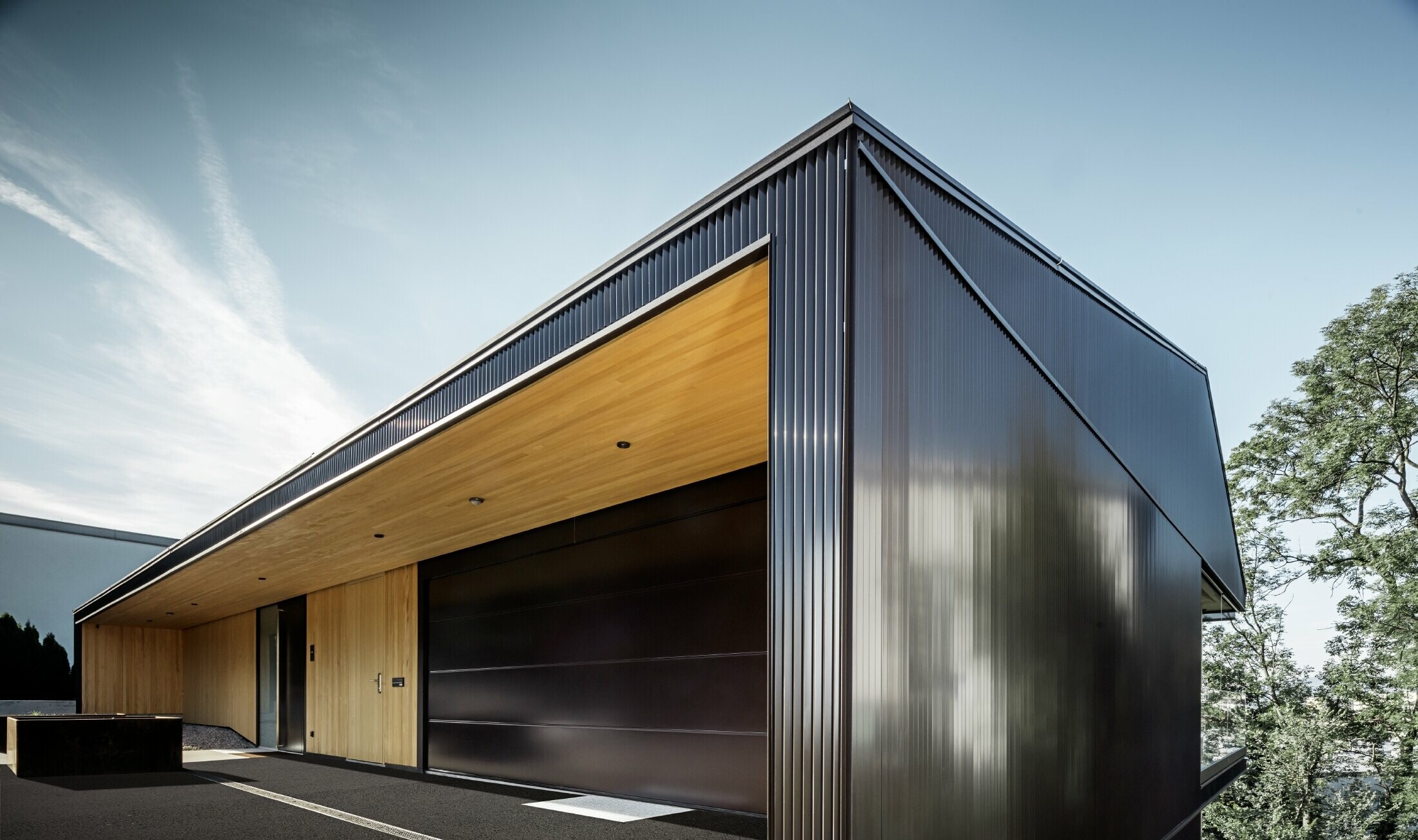 Ulaz u garažu obiteljske kuće, fasada je obložena PREFA zupčastim profilom u tamno smeđoj. 