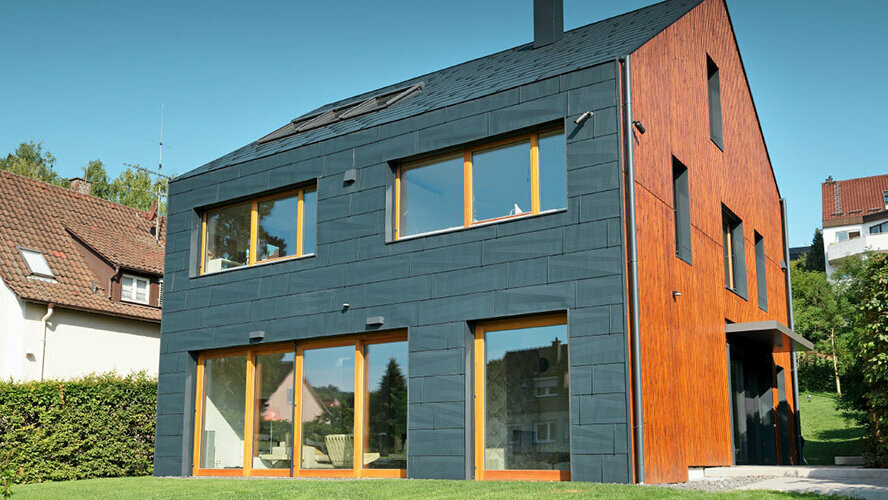 PREFA fasada s panelom FX.12 u P.10 antracit boji savršeno se stapa s dvostrešnim krovom bez strehe.