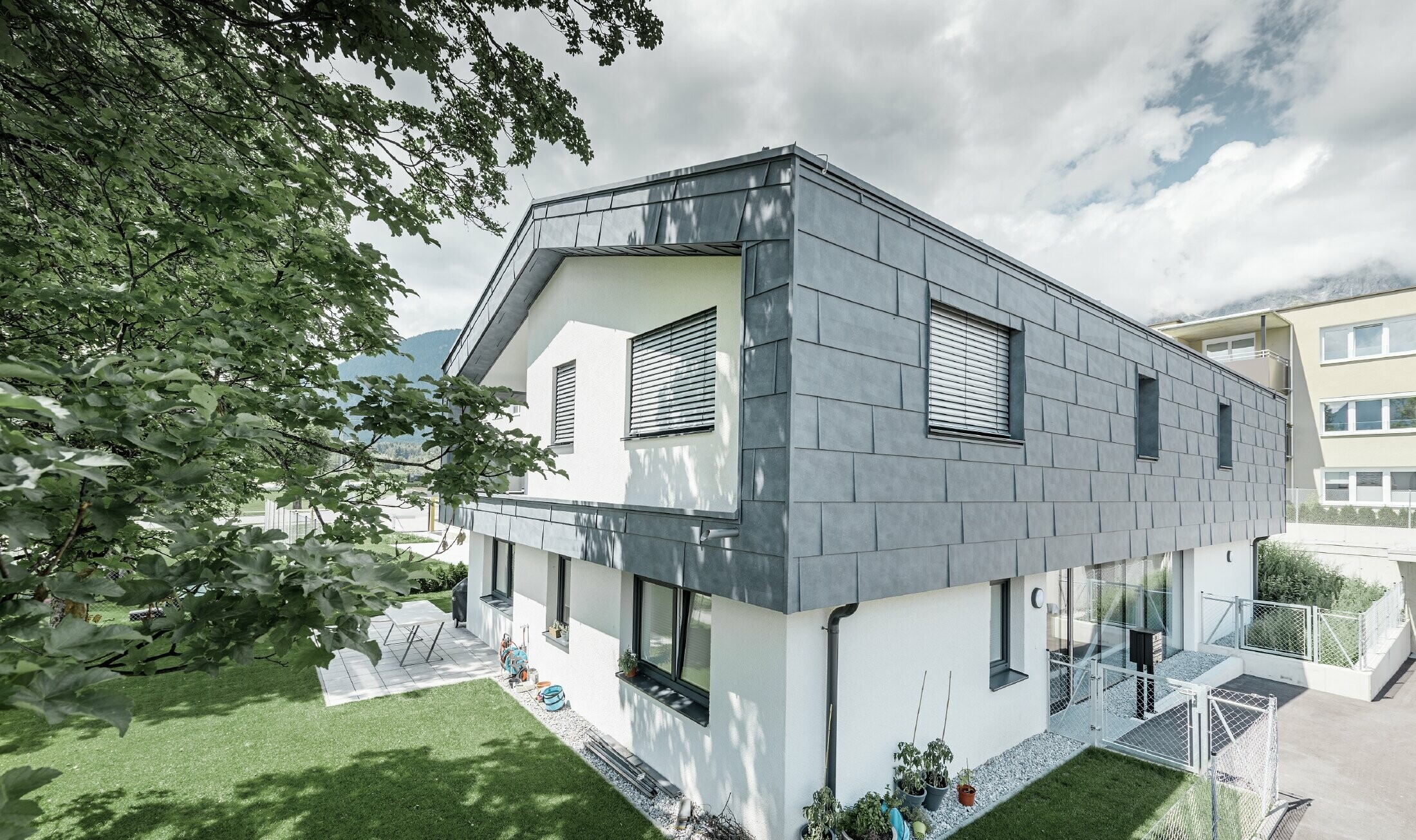 Moderan dignut kat stambene kuće s ravnim dvostrešnim krovom i bez strehe; Fasadna obloga izrađena je s PREFA fasadnim panelom FX.12 u kameno sivoj.