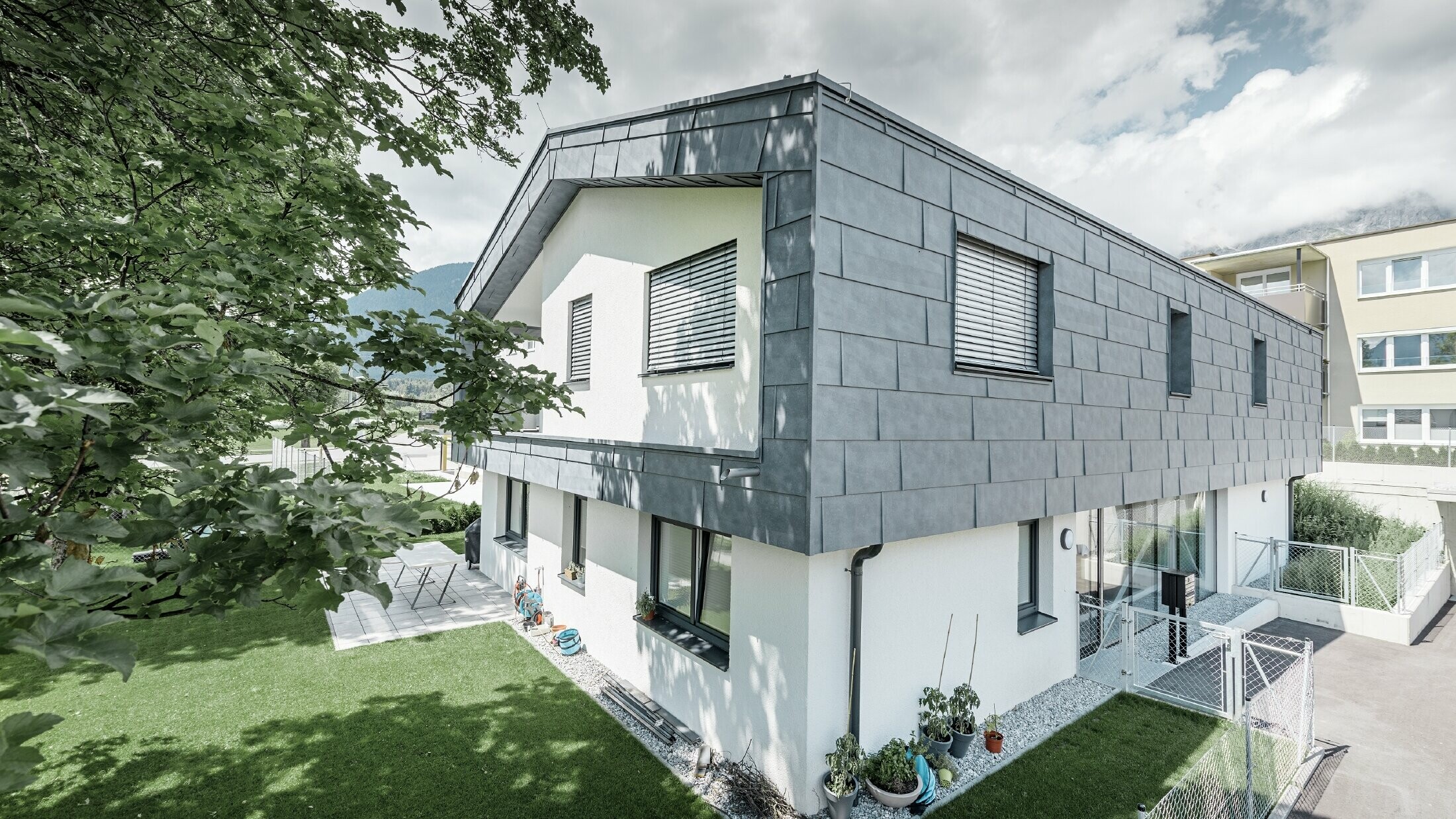 Moderan dignut kat stambene kuće s ravnim dvostrešnim krovom i bez strehe; Fasadna obloga izrađena je s PREFA fasadnim panelom FX.12 u kameno sivoj.