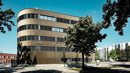 Dinamičan arhitektonski pogled na Policijsku postaju 43 u Hamburgu otkriva zakrivljenu novogradnju s PREFA aluminijskom fasadom od ekstrudiranih zupčastih profila u srednje brončanoj nijansi. Kao upečatljiv arhitektonski element u gradskom pejzažu, fasada privlači pažnju svojom fino strukturiranom površinom koja stvara živopisnu igru svjetla i sjene između horizontalnih prozorskih nizova te naglašava fluidne linije objekta. PREFA aluminij pruža izvrsnu otpornost na koroziju, dug vijek trajanja i minimalno održavanje – idealno rješenje za održive, funkcionalne i precizno oblikovane fasadne koncepte