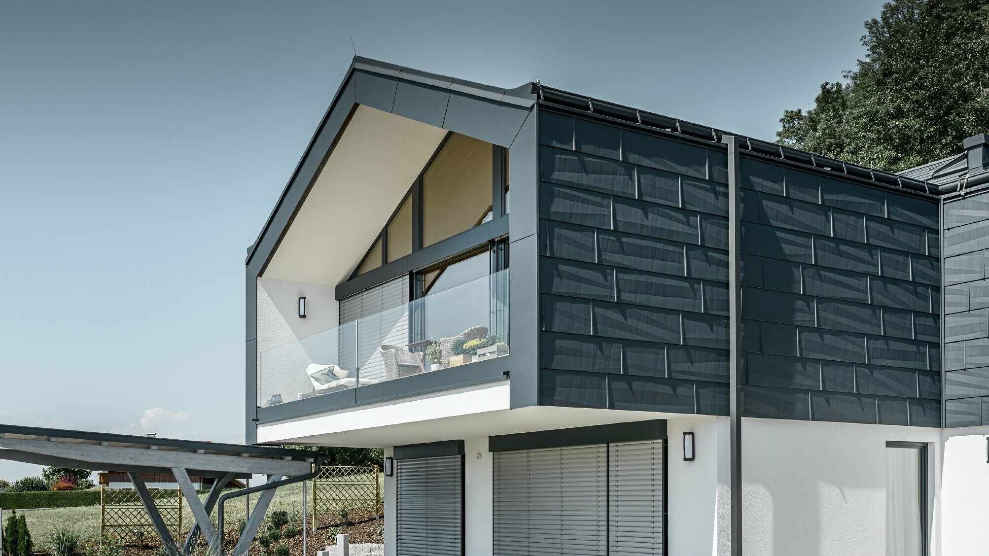 Moderna višeobiteljska kuća s velikim ostakljenim pročeljem, krov i fasada obloženi su krovnim i fasadnim panelima FX.12 u antracit boji od PREFE