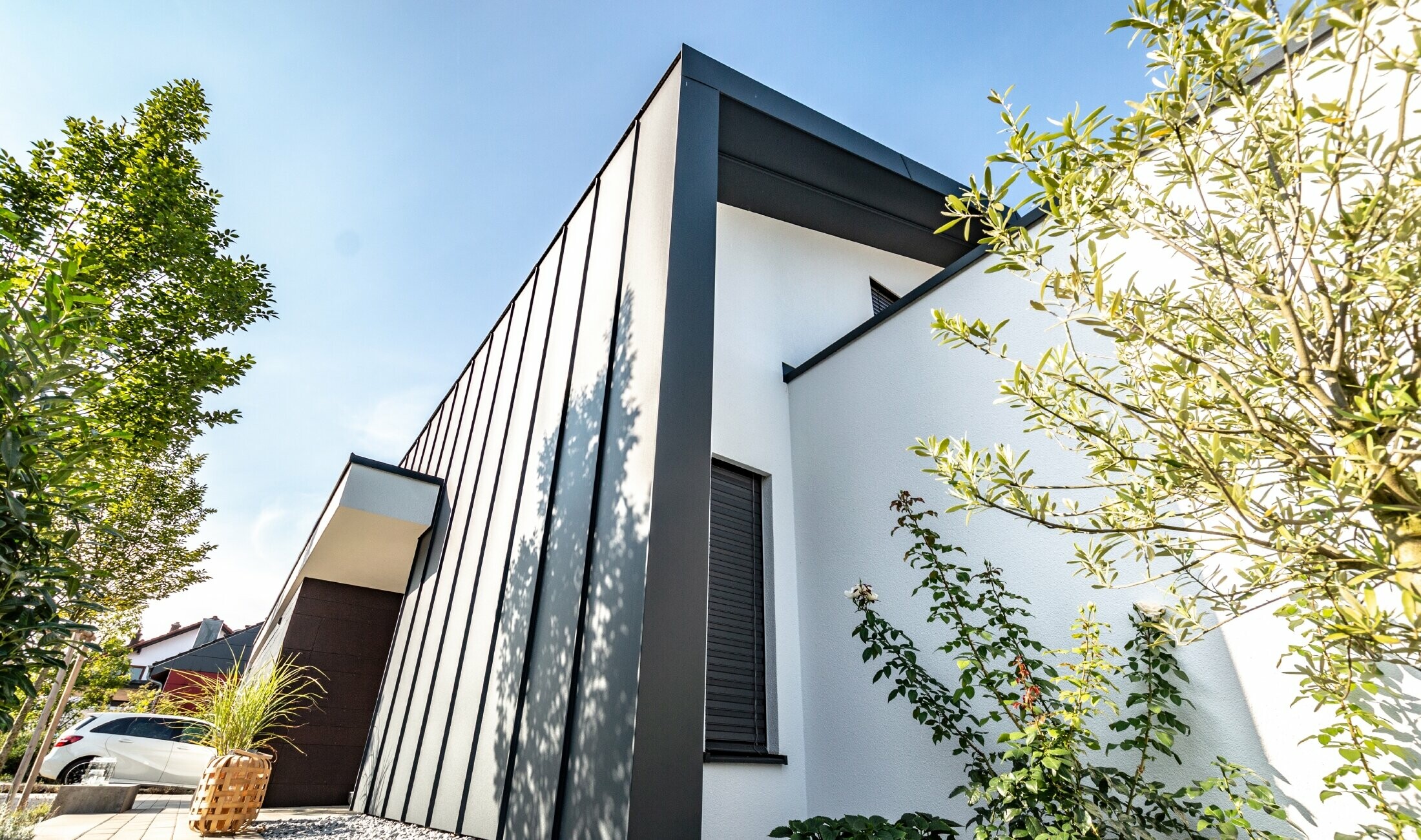 Fasada od Prefalza tvrtke PREFA u antracit boji također se proteže preko dvostrešnog krova obiteljske kuće.