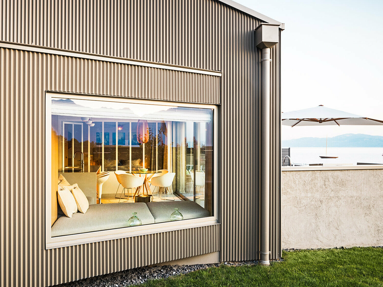 Bočni prikaz zgrade sa zupčastom aluminijskom fasadom, u kadru je dio osvijetljenog interijera.