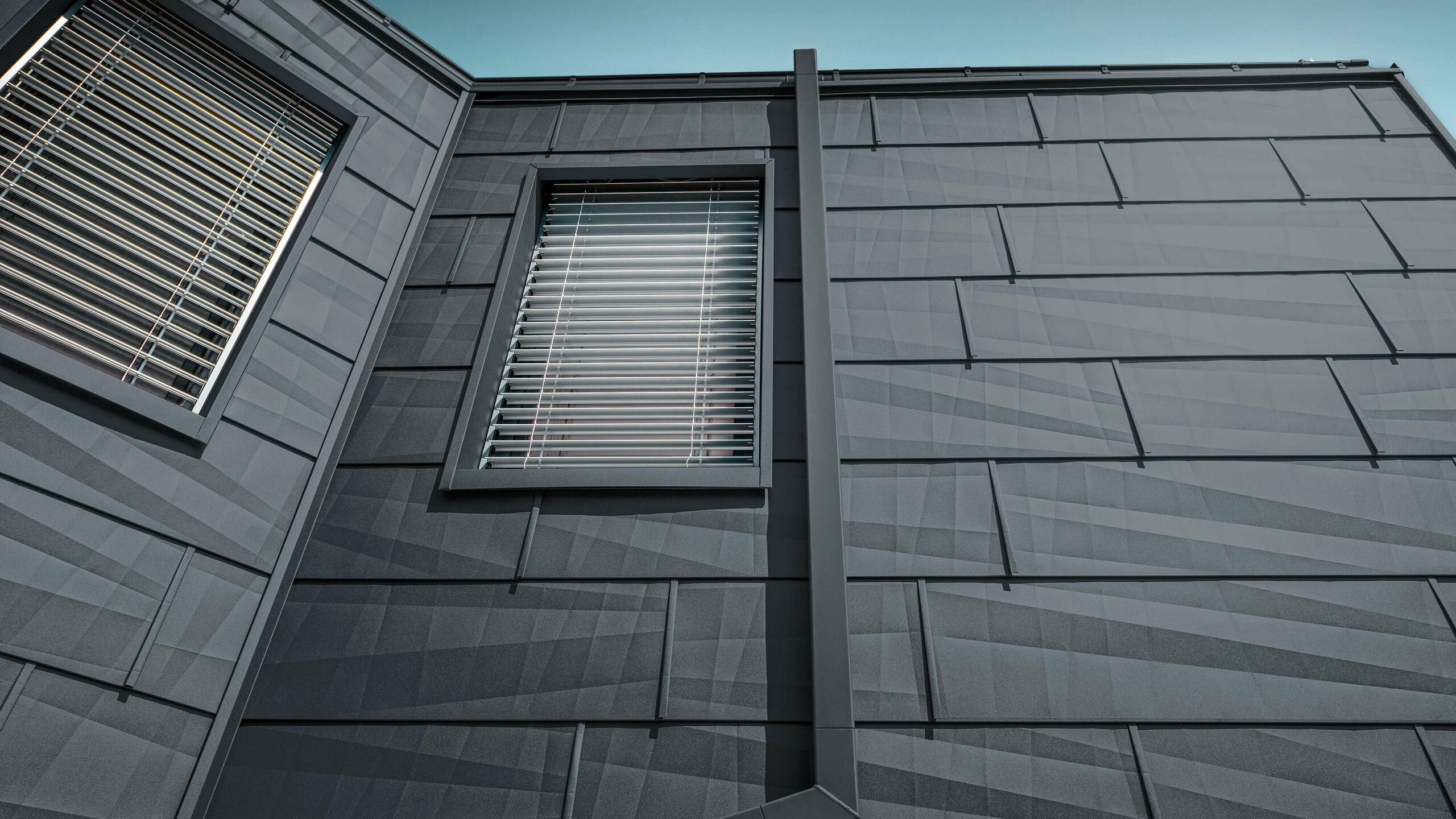 Fasade obložene PREFA fasadnim panelom FX.12 u antracit boji, aluminijski paneli na fasadi s kutnom odvodnom cijevi, kvadratnom cijevi, u antracit boji od tvrtke PREFA.