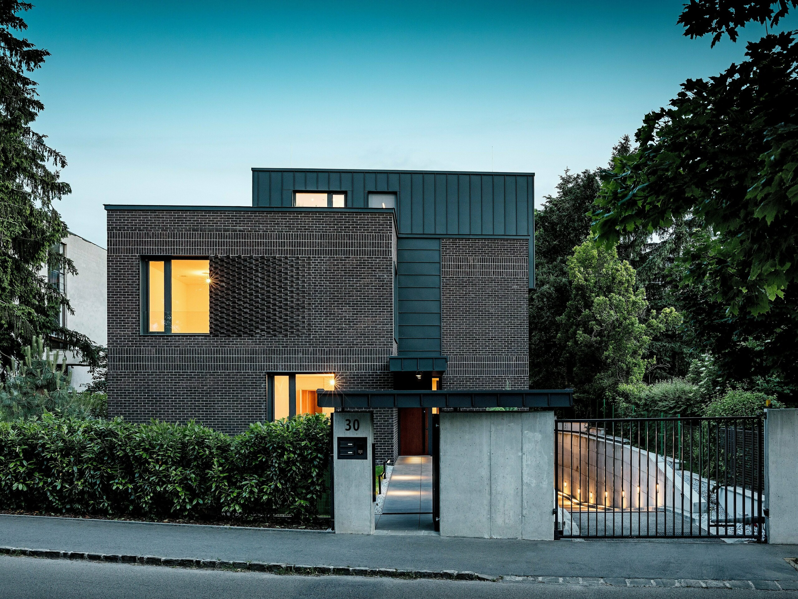 Snimka prikazuje modernu stambenu kuću u Budimpešti, čiji kubični krov od PREFALZ aluminija u boji P.10 antracit stvara upečatljiv kontrast prema povijesnom okruženju. Vertikalni stojeći falcevi stvaraju zanimljivu igru svjetla i naglašavaju jasni arhitektonski izraz. Visokokvalitetni PREFA aluminijski proizvodi daju zgradi ne samo elegantan i bezvremenski izgled, već se odlikuju i dugotrajnošću, otpornosti na vremenske uvjete i preciznom izradom. Antracitni dio fasade i krova predstavlja snažan vizualni naglasak i ističe inovativni karakter građevine.