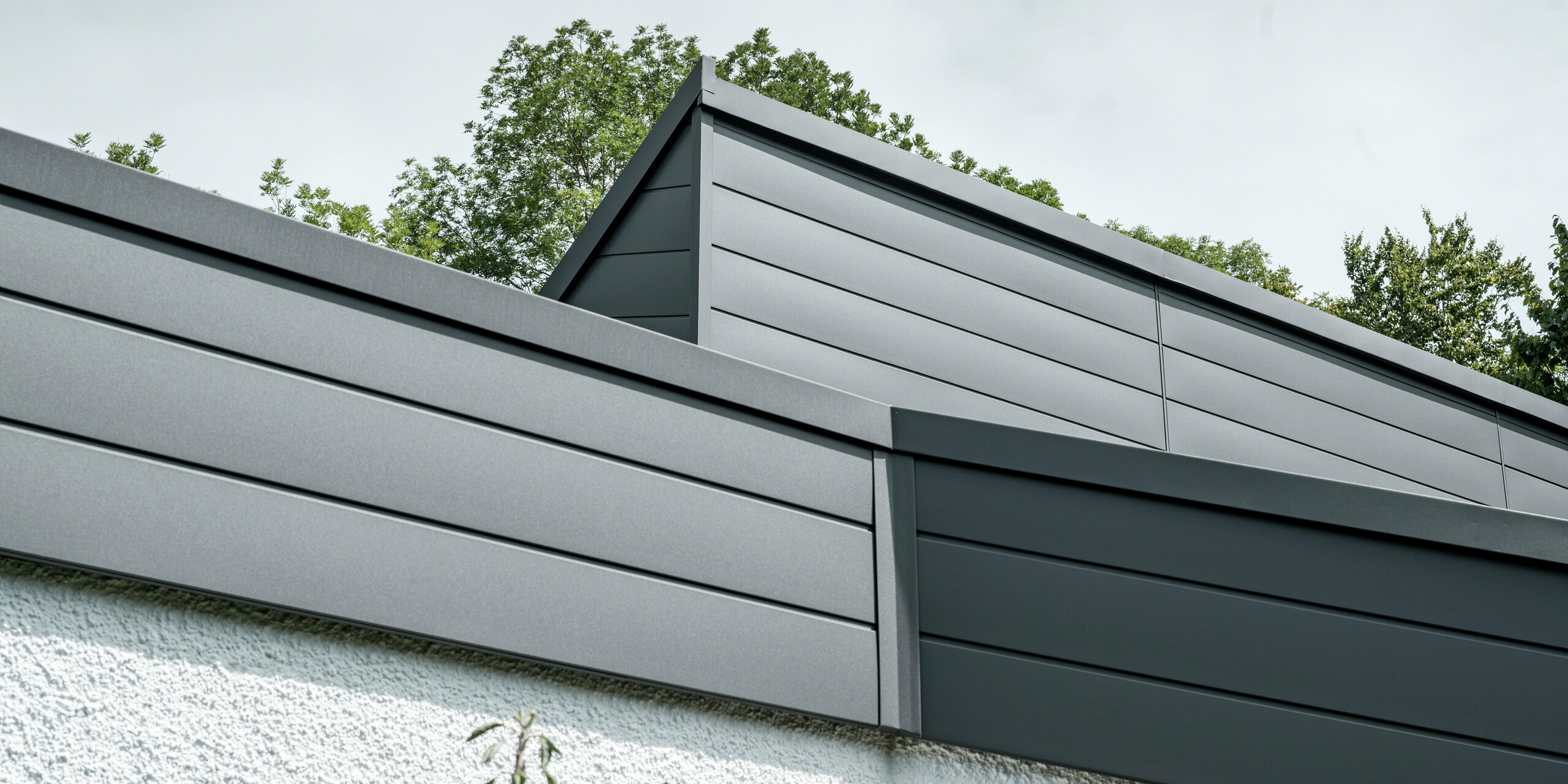 Ein Einfamilienhaus, das mit PREFA Dachschindeln DS.19 in schwarz eingedeckt wurde. Für Teile der Fassade wurden PREFA Sidings in P.10 dunkelgrau verwendet. 