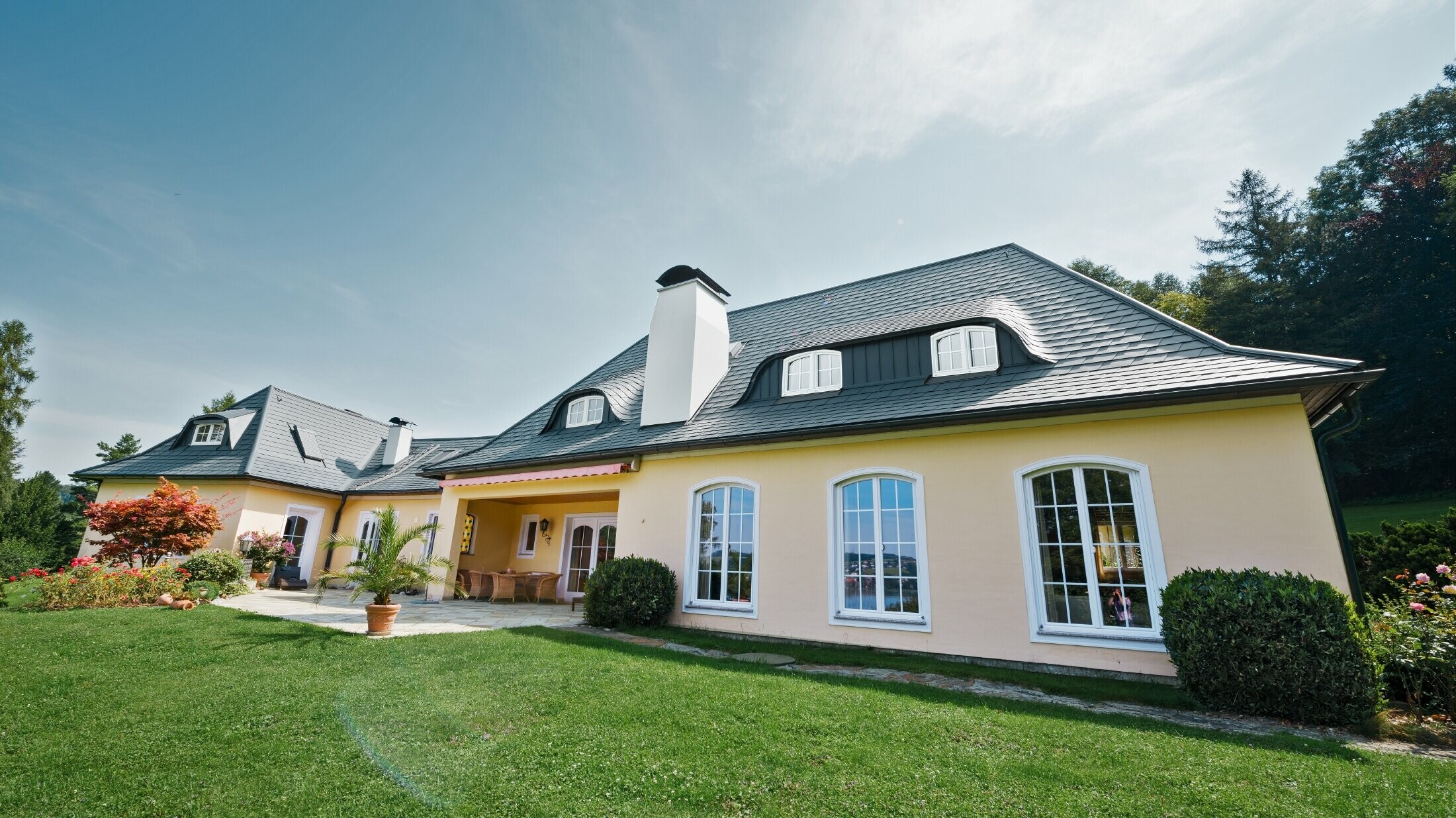 Klasična obiteljska kuća sa zaobljenom krovom kućicom, pokrivena PREFA šindrom otpornom na nevrijeme, s 40-godišnjim jamstvom za materijal.