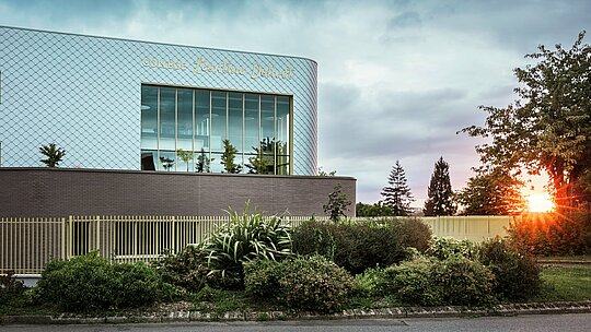 Moderni školski objekt Collège Léontine Dolivet u Cesson-Sévignéu s upečatljivom aluminijskom fasadom od otprilike 15.000 PREFA zidnih rombova u srebrno-metalik boji. Sjajna površina reflektira svjetlo i stvara živopisni, elegantni izgled. Velike staklene površine otvaraju pogled na zelenilo, dok robusno PREFA rješenje fasade jamči dugovječnost i otpornost na vremenske uvjete. Kombinacija promjenjivog metala i jasne arhitekture čini zgradu pravim privlačnim objektom i ističe prednosti aluminija: lagan, bez održavanja i održiv.