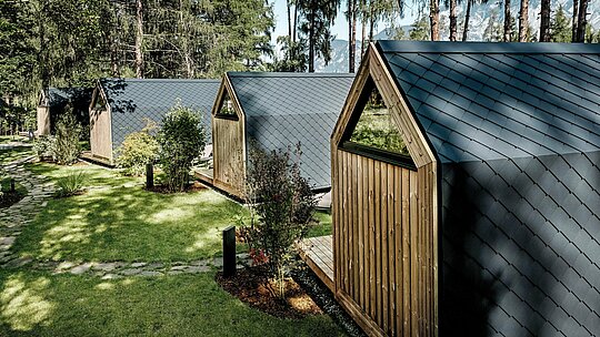 Niz minimalističkih tiny kuća Secret Koi Gardena proteže se u uređenom zelenom kompleksu uz jezero Natterer See. Nagnuti krovovi i fasade izvedeni su od sitnih PREFA aluminijskih rombova u P.10 antracitnoj boji, koji stvaraju smirenu strukturu nalik ribljoj koži.  Okružene drvećem i grmljem, dugotrajne i vremenski otporne PREFA aluminijske površine pružaju optimalnu zaštitu te daju glamping resortu jasnu, bezvremensku arhitektonsku izražajnost u skladu s prirodom.