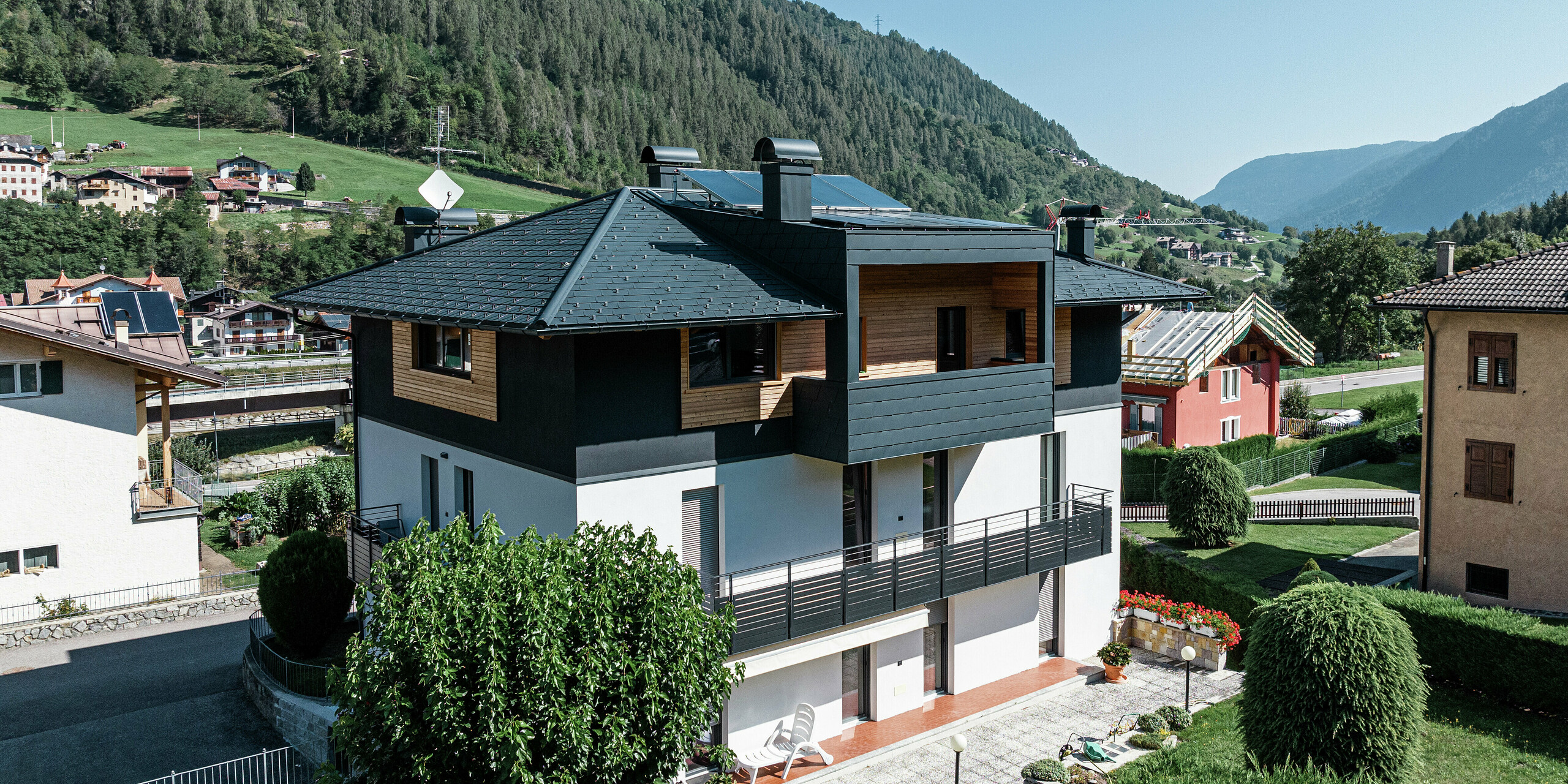 Vogelperspektive auf das Wohnhaus in Commezzadura mit PREFA Dachschindeln DS.19 in P.10 Anthrazit. Teile der Fassade des Dachgeschosses wurden mit Holz verkleidet, wodurch ein harmonischer Gesamteindruck entsteht. Auch die überdachten Balkone sind mit dem hochwertigen Aluminiumprodukt eingedeckt.