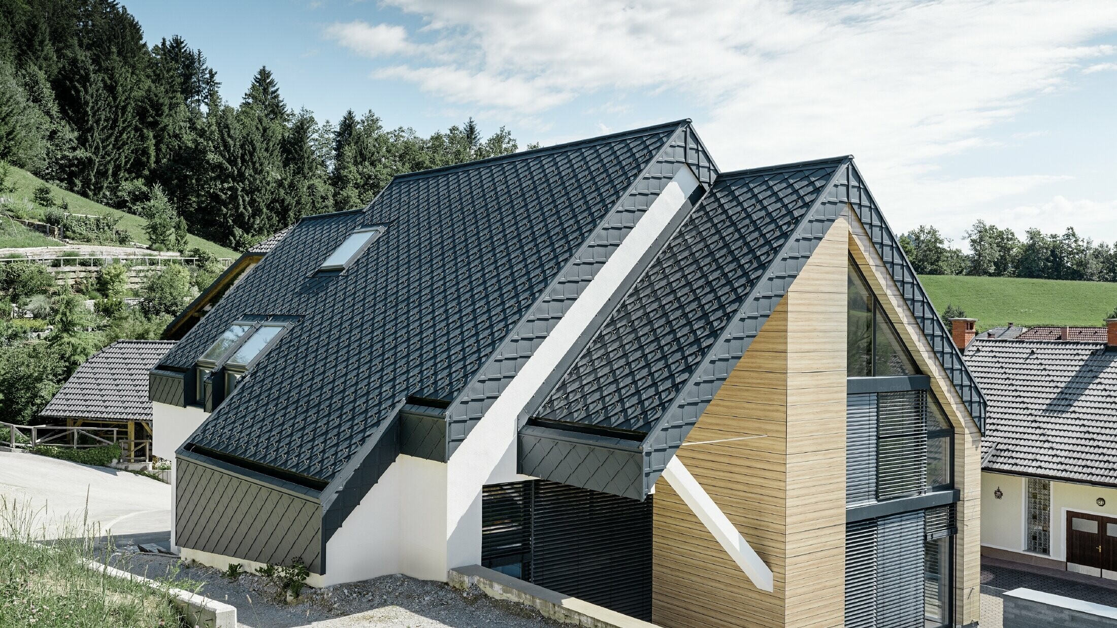 Obiteljska kuća s dvostrešnim krovom bez nadstrešnice s fasadom u optici drva i aluminijskim krovom u antracit boji