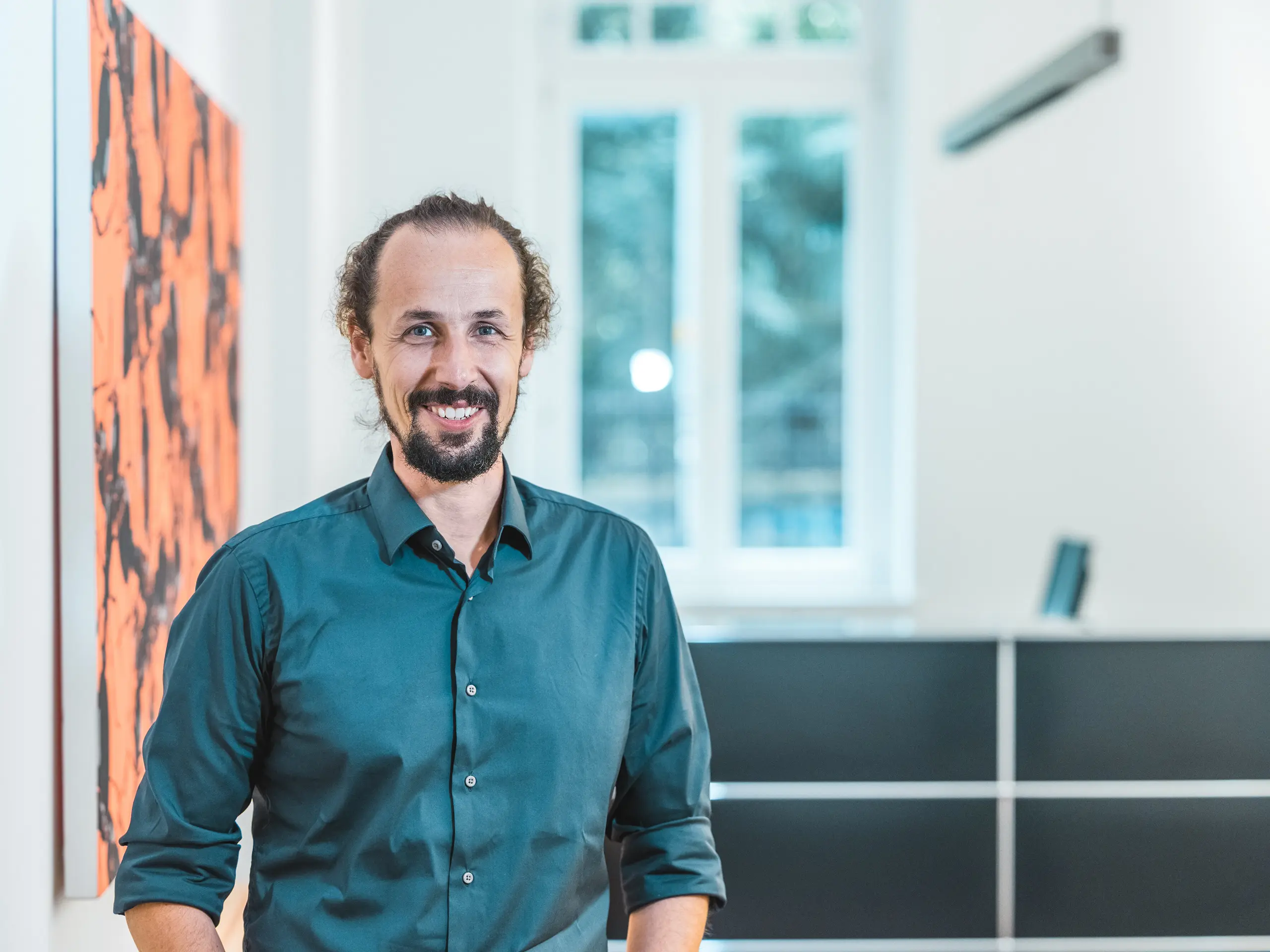 Portret arhitekta Gianfranca Berardesce u modernom interijeru. Voditelj projekta u uredu Höller & Klotzner Architekten pratio je realizaciju obrazovnog centra u Rifianu u Južnom Tirolu. Nagrađeni projekt PREFARENZEN izveden je s PREFA krovnim rombovima dimenzija 44 × 44 cm u boji P.10 Bronze te predstavlja primjer preciznog planiranja, arhitektonske kvalitete i južnotirolskog obrtništva.