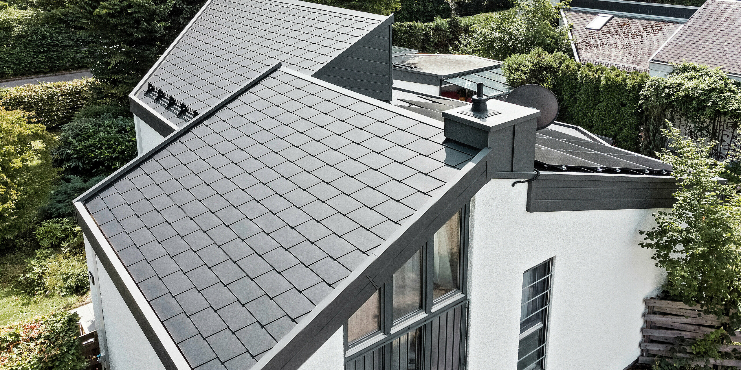 Ein Einfamilienhaus, das mit PREFA Dachschindeln DS.19 in schwarz eingedeckt wurde. Für Teile der Fassade wurden PREFA Sidings in P.10 dunkelgrau verwendet. 