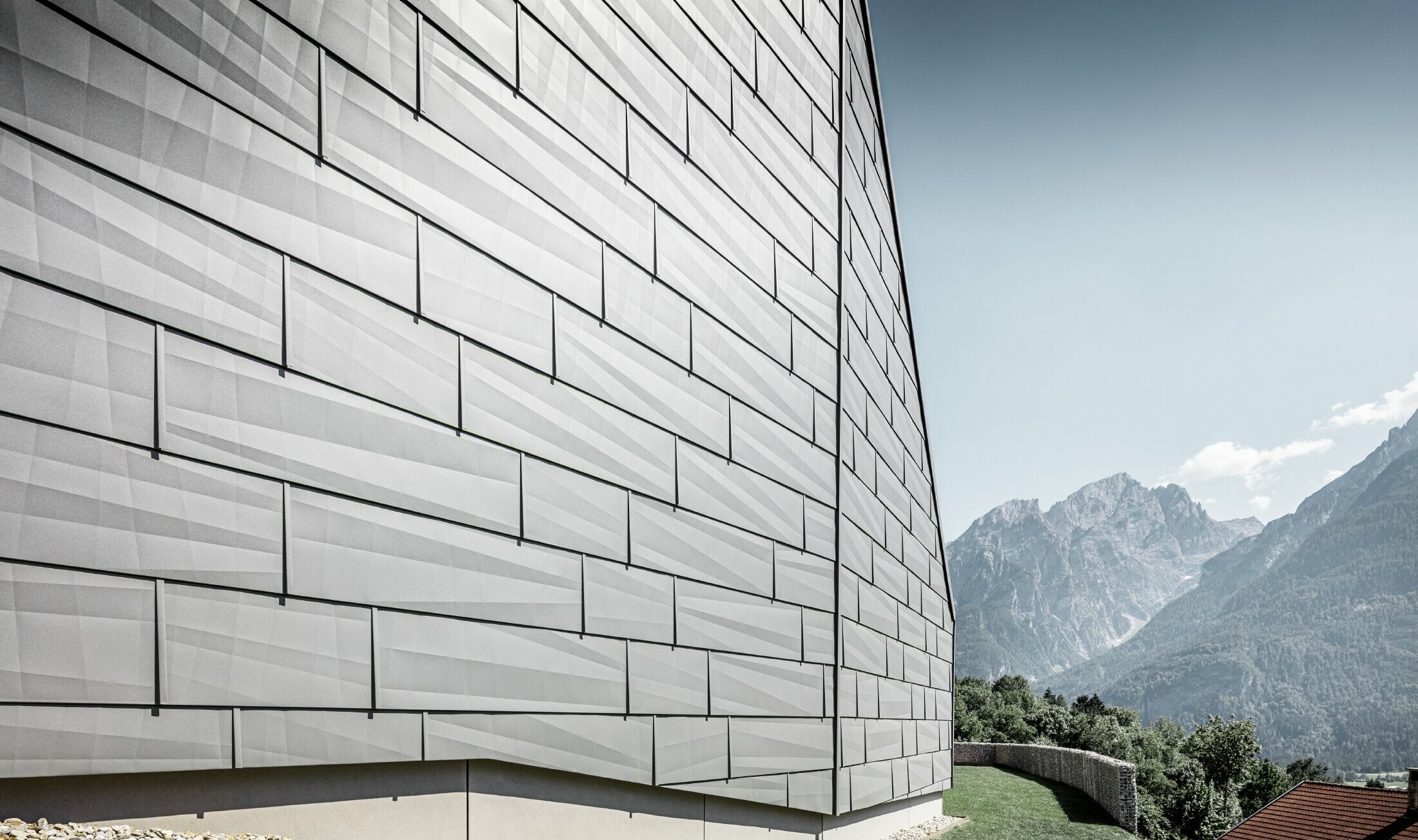 Strana izložena vremenskim utjecajima obiteljske kuće u Lienzu, Austrija, obložena je PREFA fasadnim panelom FX.12 u P.10 svijetlo sivoj.