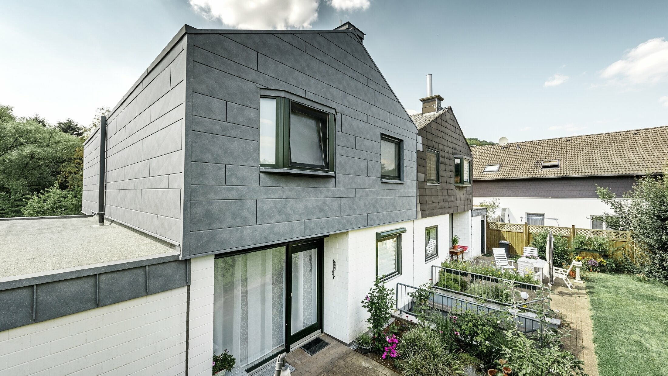 Gornji dio polovice dvostruke kuće saniran je PREFA fasadnim elementom Siding.X u P.10 kameno sivoj. Odmah pored za usporedbu polovica kuće prije sanacije.