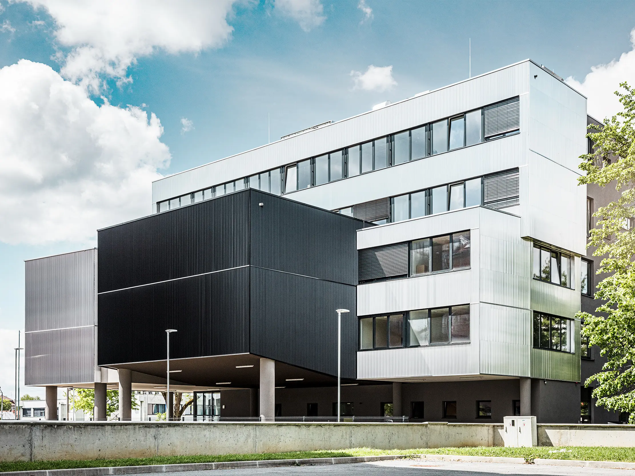Bočni prikaz glazbene škole u Bjelovaru s modernom PREFA fasadom od zupčastog profila. Fasada je izrađena od crnih i natur aluminij profila, a geometrijski oblici pružaju upečatljiv, minimalistički dizajn.