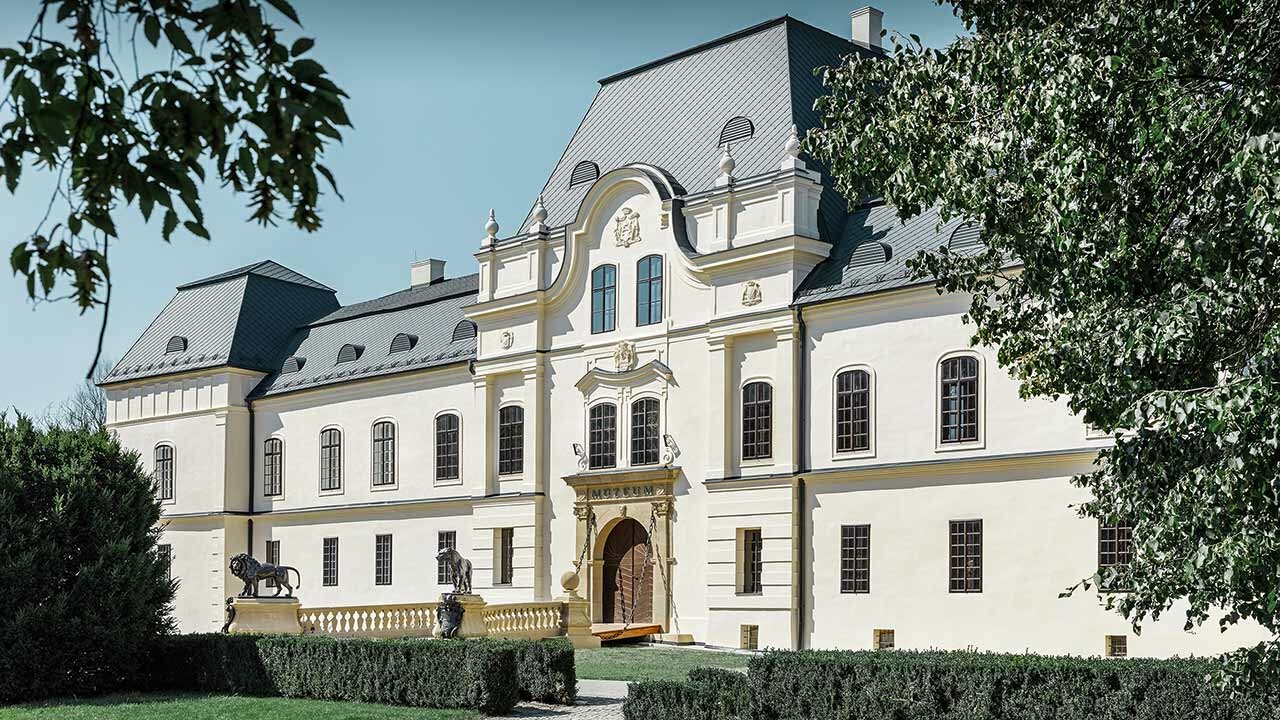 bočni pogled na dvorac Humenné s drvećem u prvom planu, sanacija krova PREFA krovnom pločom u antracit boji
