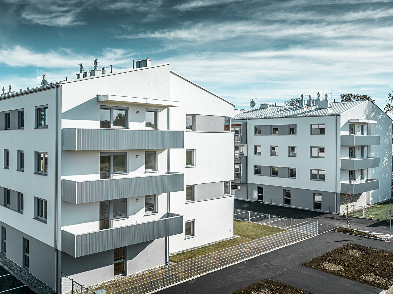Moderan stambeni kompleks s bijelom fasadom i balkonima s PREFA zupčastim profilom u metalik srebrnoj boji