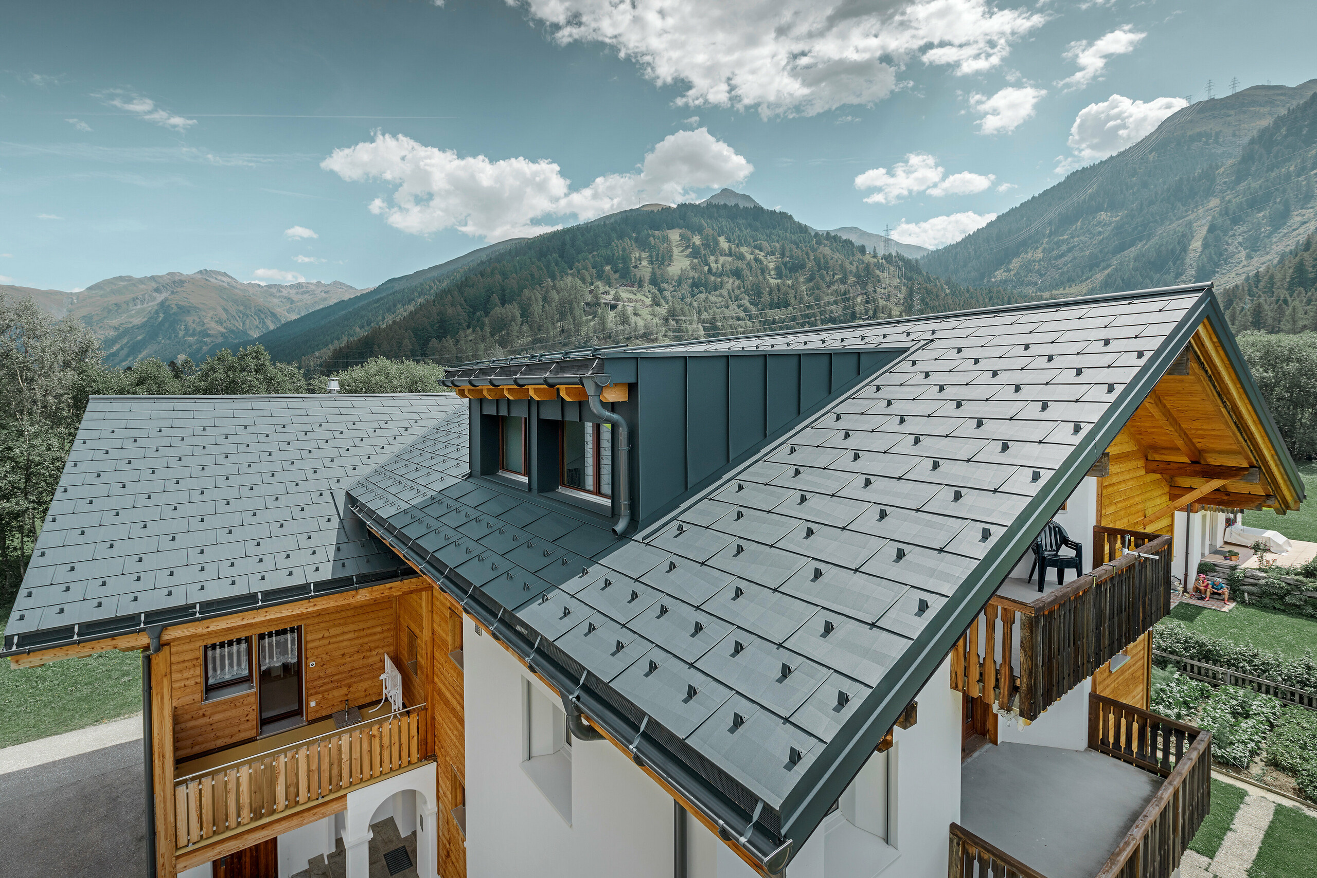 Novo sanirana stambena kuća s dvostrešnim krovom i krovnom kućicom; Sanacija krova provedena je PREFA krovnim panelom FX.12 u antracit boji.