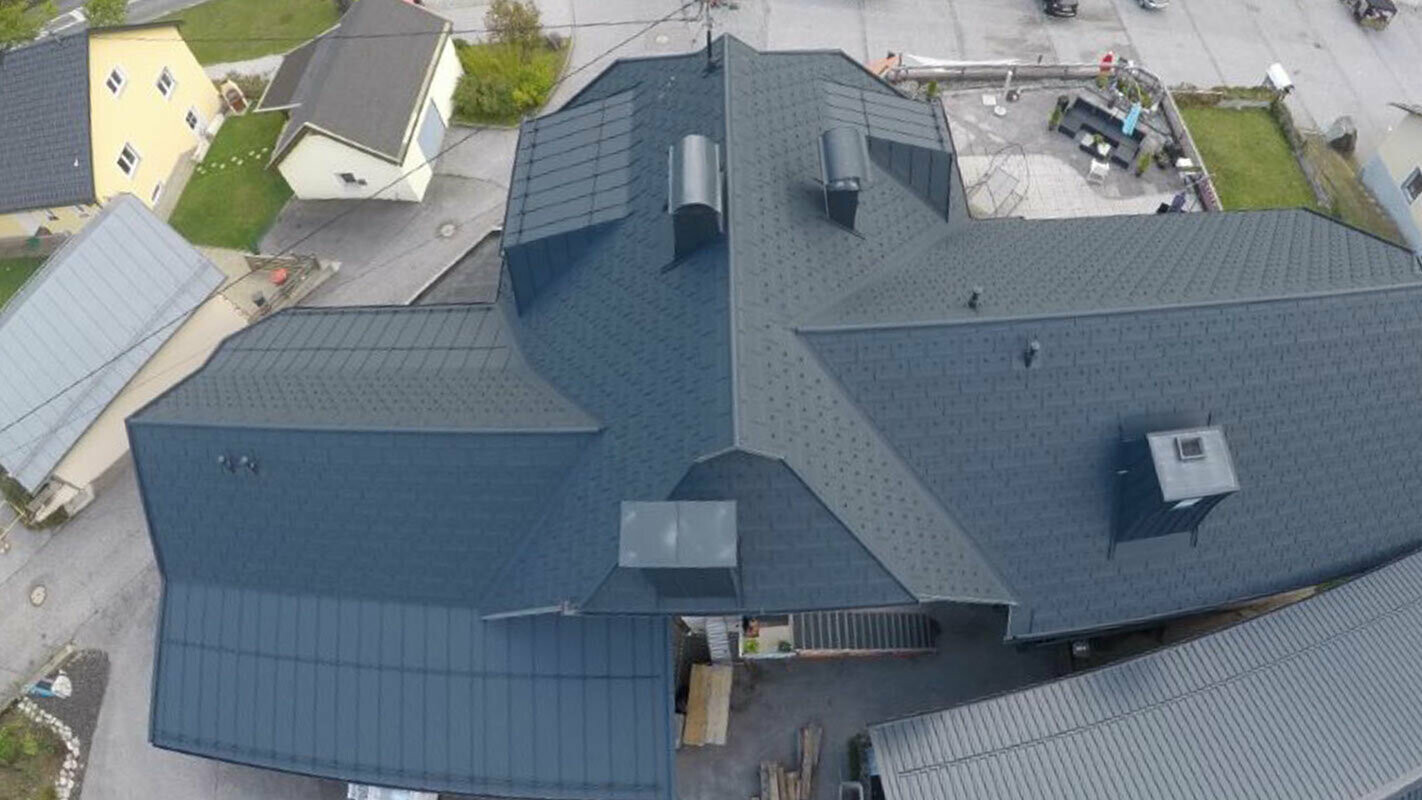 Sanacija velike krovne površine s puno detalja - s uvalama, krovnim kućicama i dimnjacima. Krov je pokriven aluminijskom krovnom pločom R.16 tvrtke PREFA u antracit boji.