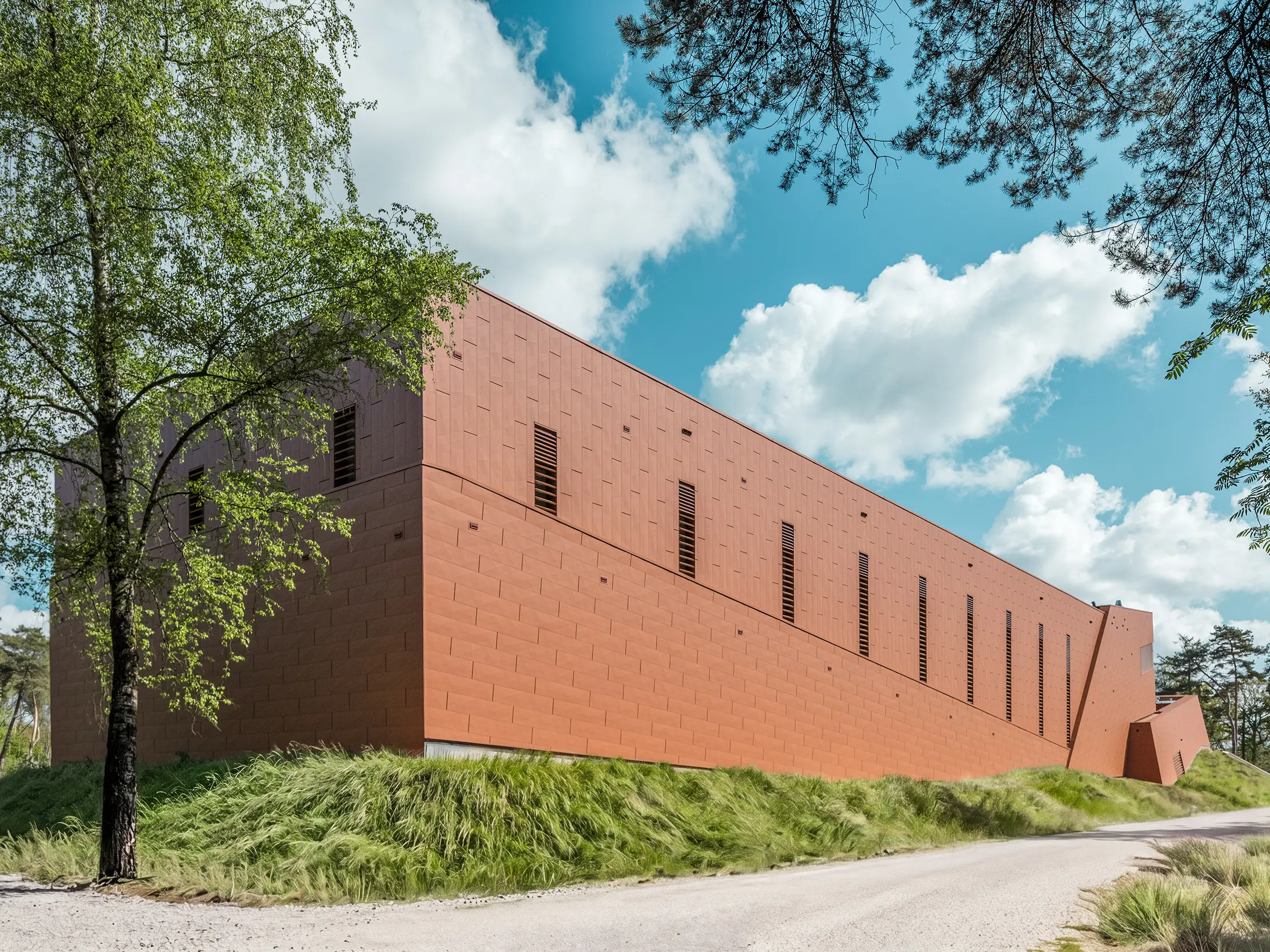 Izdužena crpna stanica za pitku vodu WML u Lottumu predstavlja se kao snažan volumen zgrade usred prirodnog krajolika drveća, livada i širokog pogleda prema nebu. Upečatljiva PREFA Siding.X aluminijska fasada u toplom izgledu hrđe privlači sve poglede kao vizualni atraktivni element i očarava svojom fino fasetiranom, živopisno strukturiranom površinom. Vitki, vertikalni otvori ritmički raščlanjuju fasadu. Dugotrajni, lagani i reciklabilni PREFA aluminijski paneli pružaju vrhunsku otpornost na vremenske uvjete, postojanost boje te održiv i jednostavan za održavanje omotač zgrade.