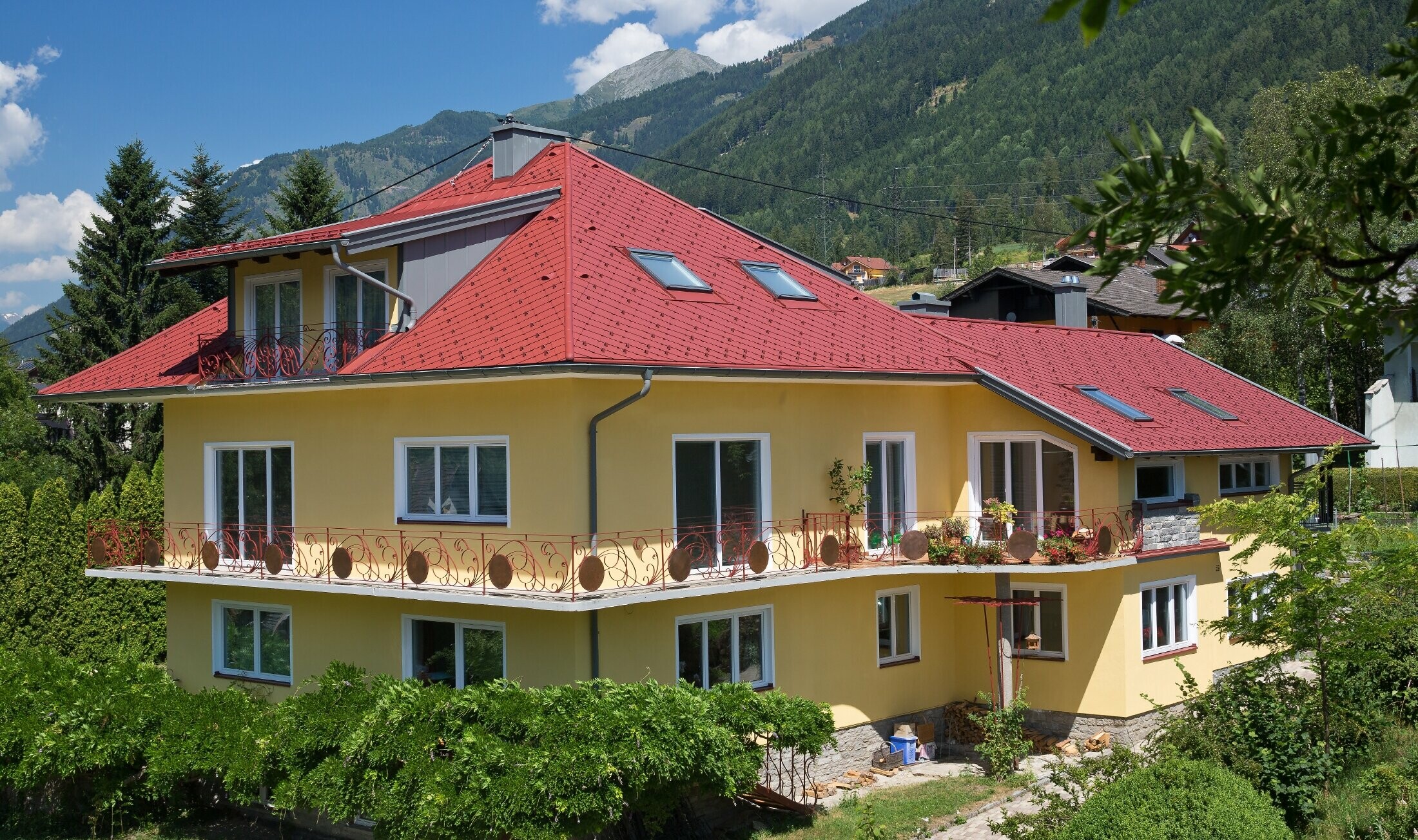 klasična obiteljska kuća s četverostrešnim krovom, pokrivena krovnim rombovima u oksid crvenoj boji.