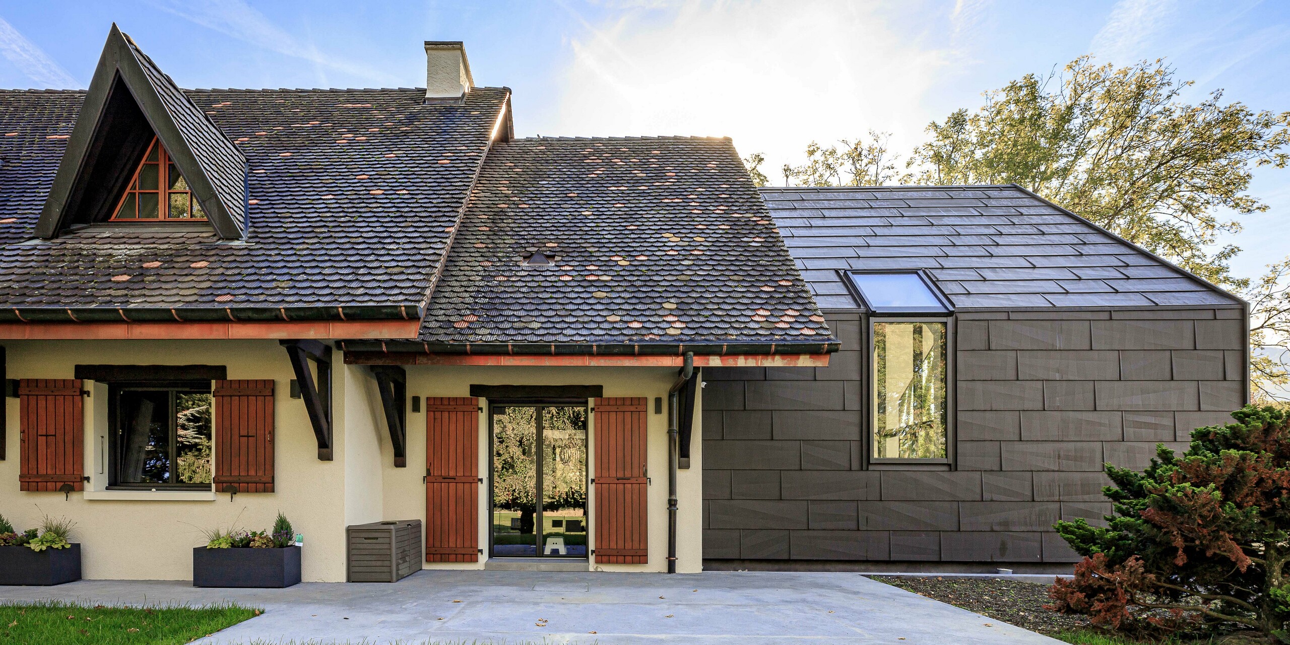 PREFA Dach- und Fassadenpaneele FX.12 in P.10 Braun als kontrastreiches Designelement auf dem Zubau eines Einfamilienhauses in Lully