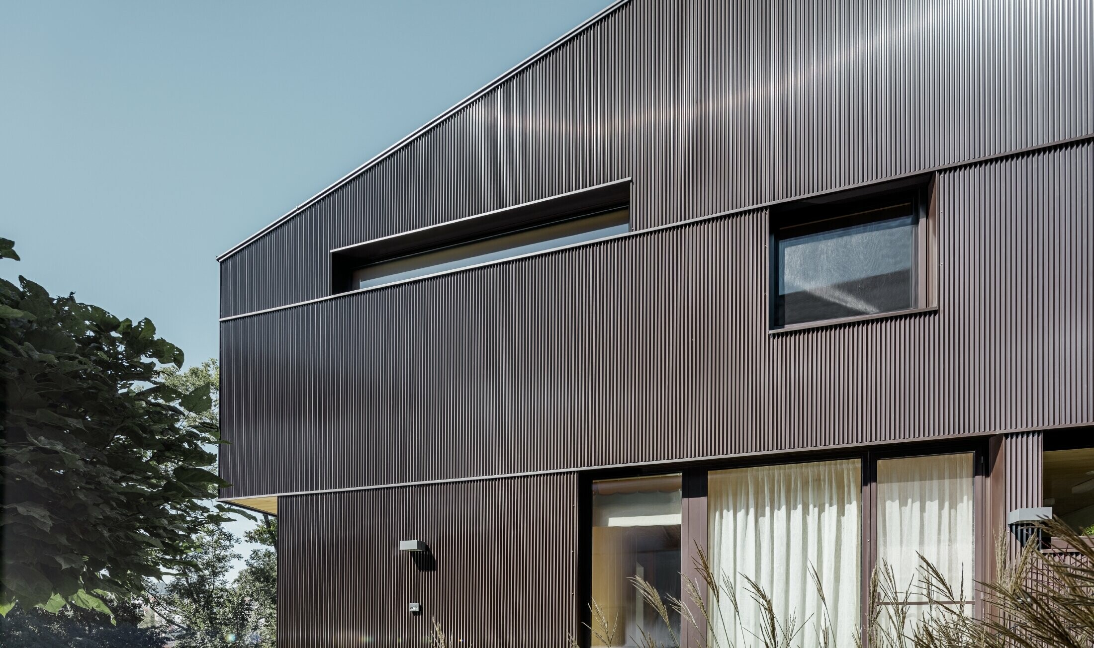 Moderna obiteljska kuća s fasadnom oblogom tvrtke PREFA – zupčasti profil u smeđoj boji.