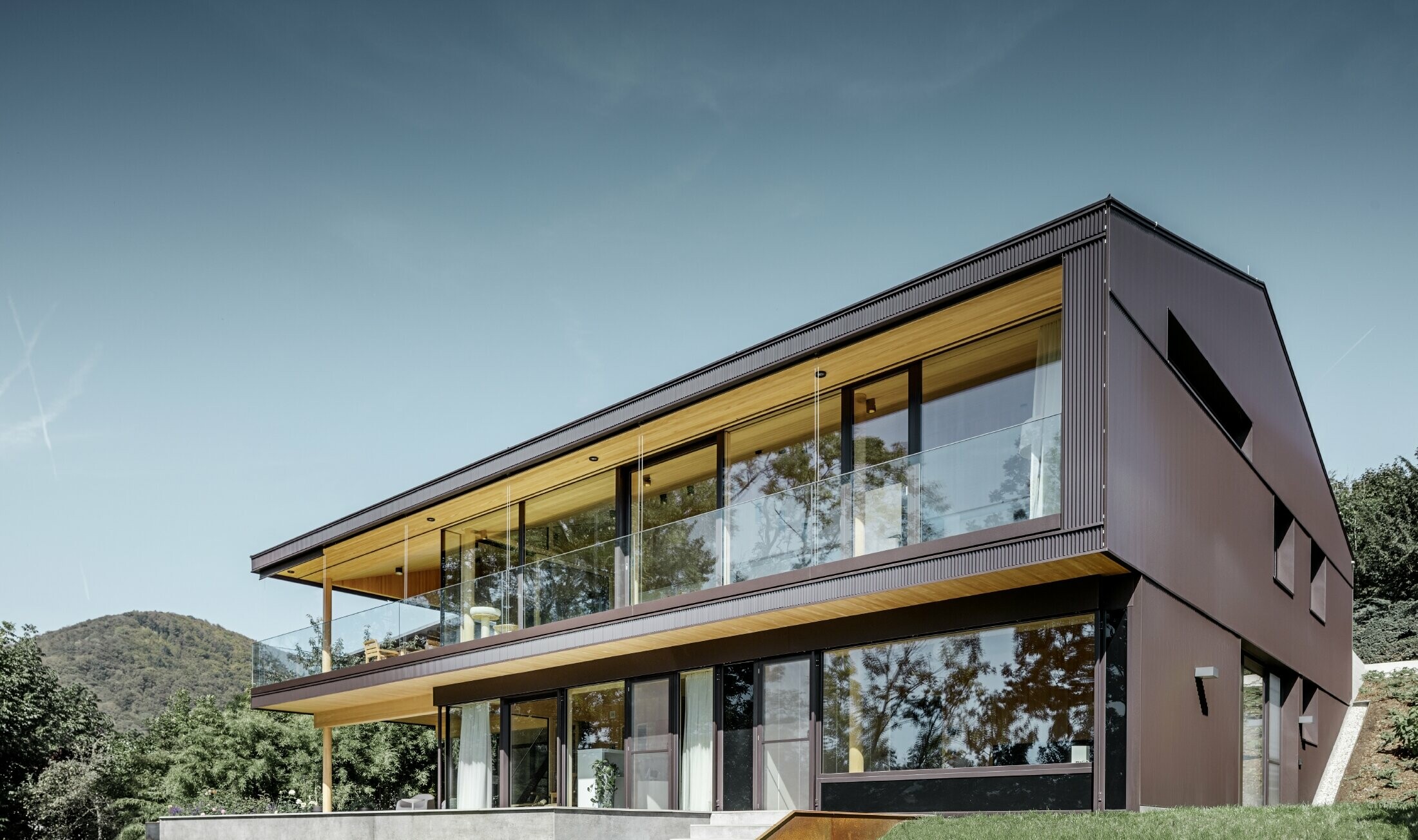 Moderna obiteljska kuća s velikim prozorima na dvorišnoj strani, fasada je obložena PREFA zupčastim profilom u tamno smeđoj.