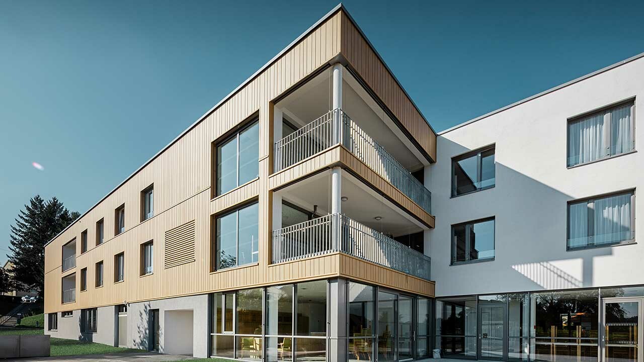 Dom za starije s ravnim krovom i pješčano smeđom fasadom iz fasadnih kazeta od PREFE